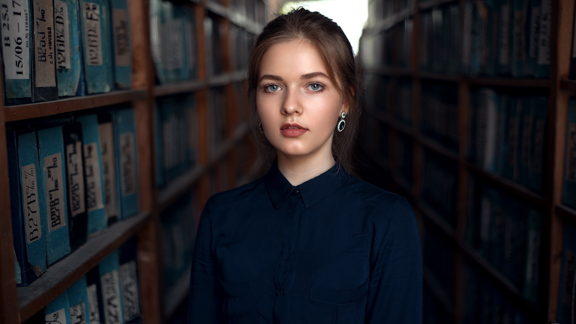 Woman in a dark blue shirt in a library HD Wallpaper