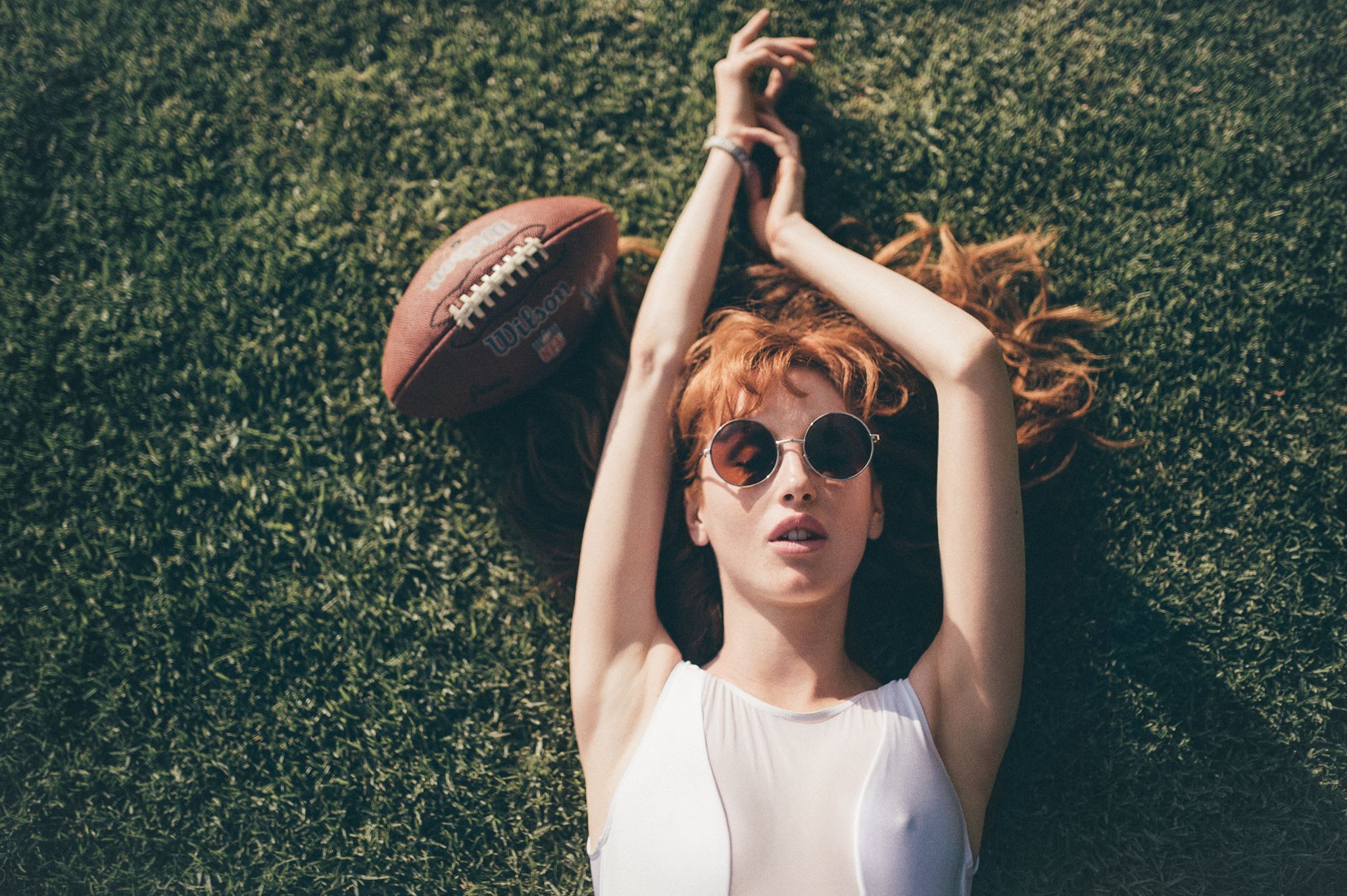 Woman with American football on grass HD Wallpaper
