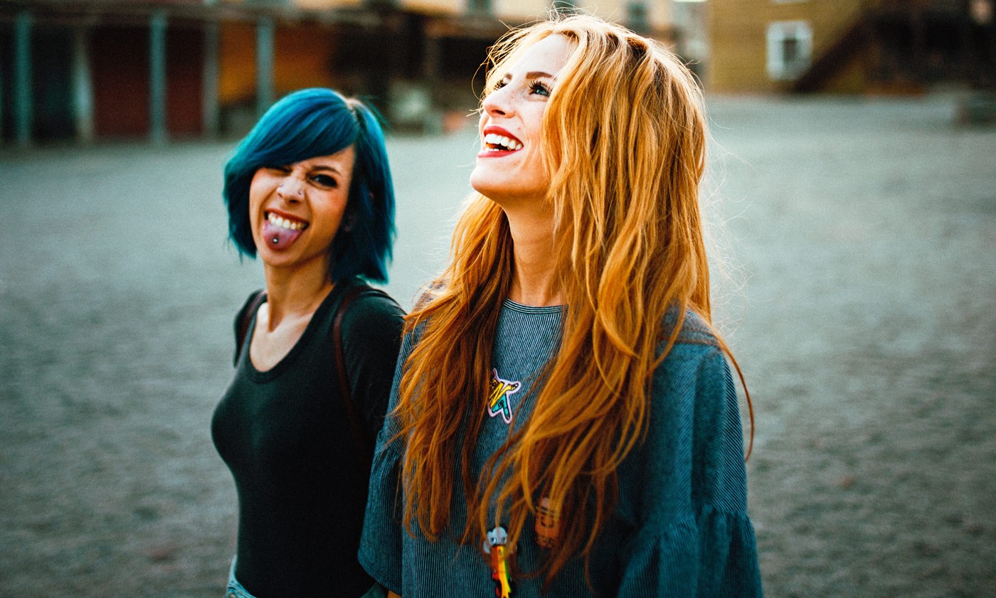 Two women with dyed hair laughing outdoors HD Wallpaper