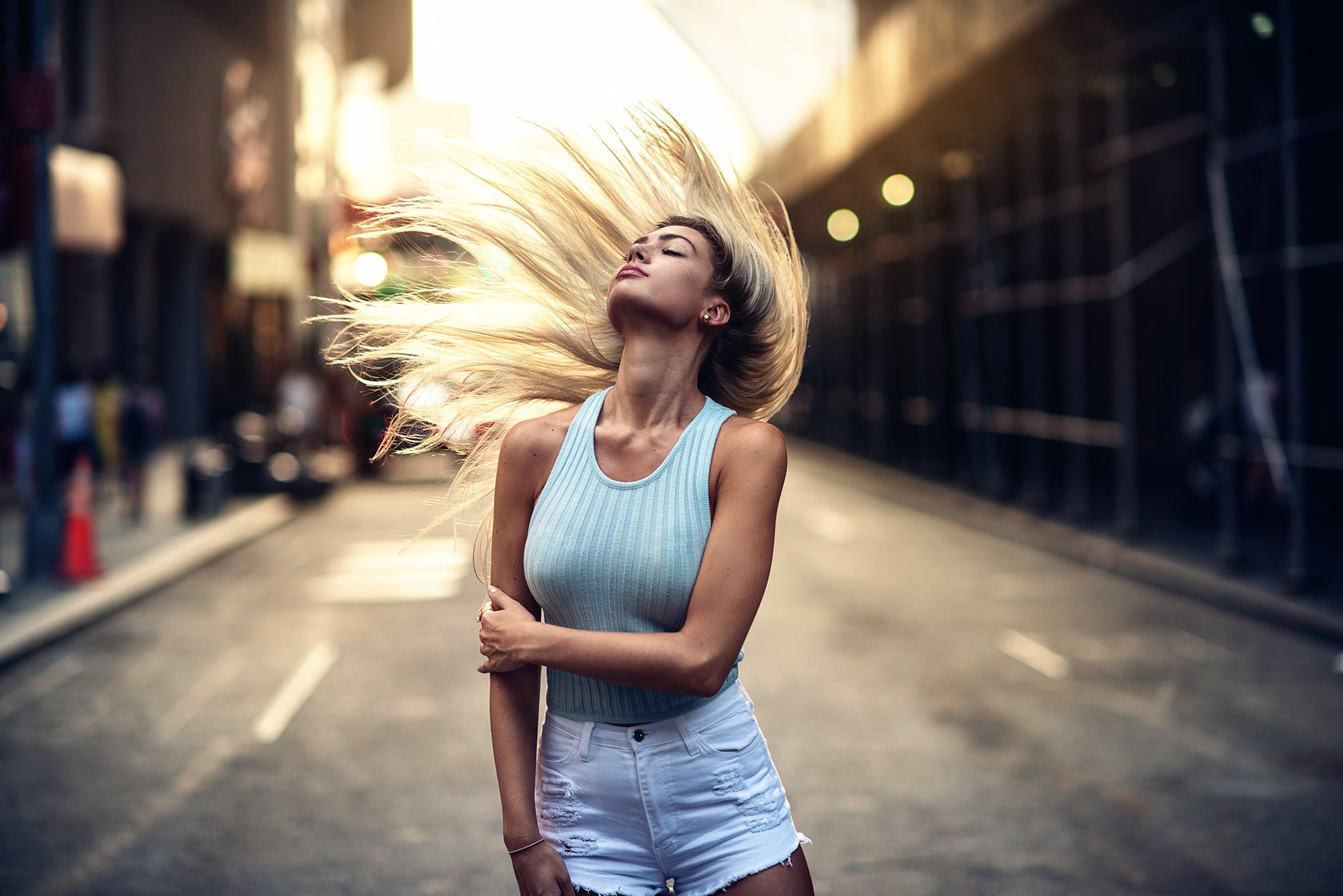 Woman with blonde hair flipping in a city street HD Wallpaper