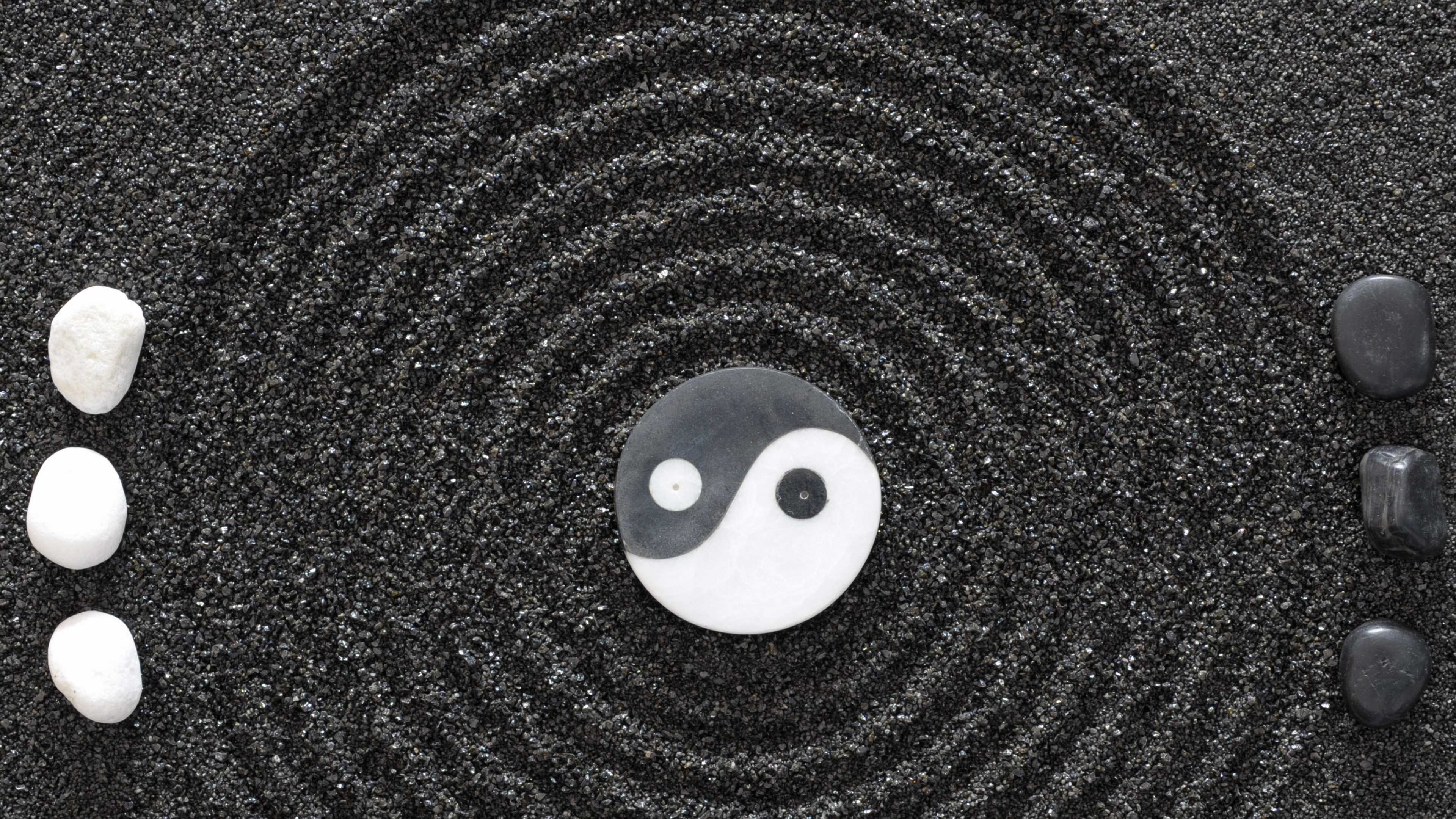 Yin and Yang symbol with stones on black sand HD Wallpaper
