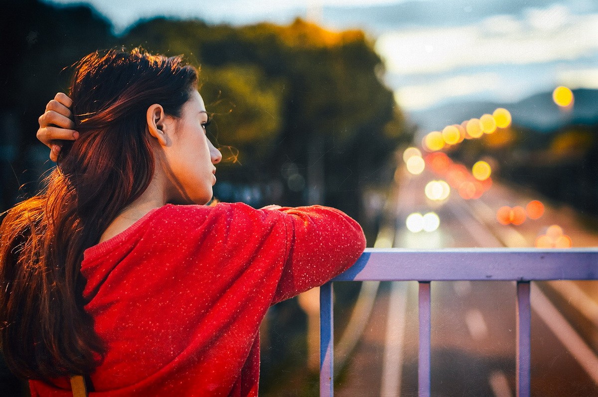 Woman in red sweater looking at city lights HD Wallpaper
