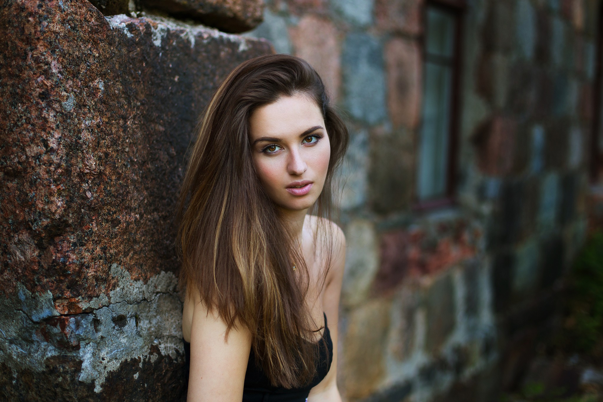 Woman leaning against a stone wall HD Wallpaper
