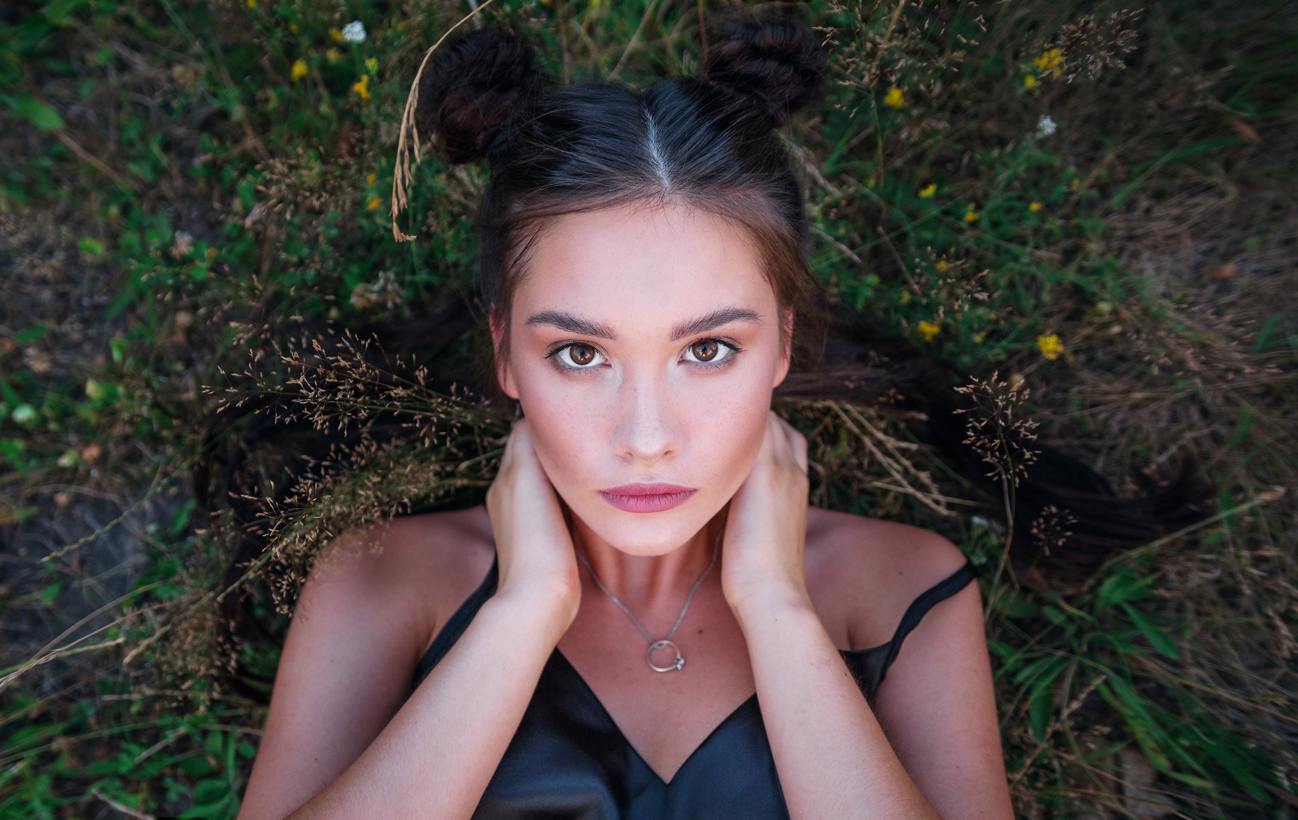 Woman with buns lying in grass HD Wallpaper