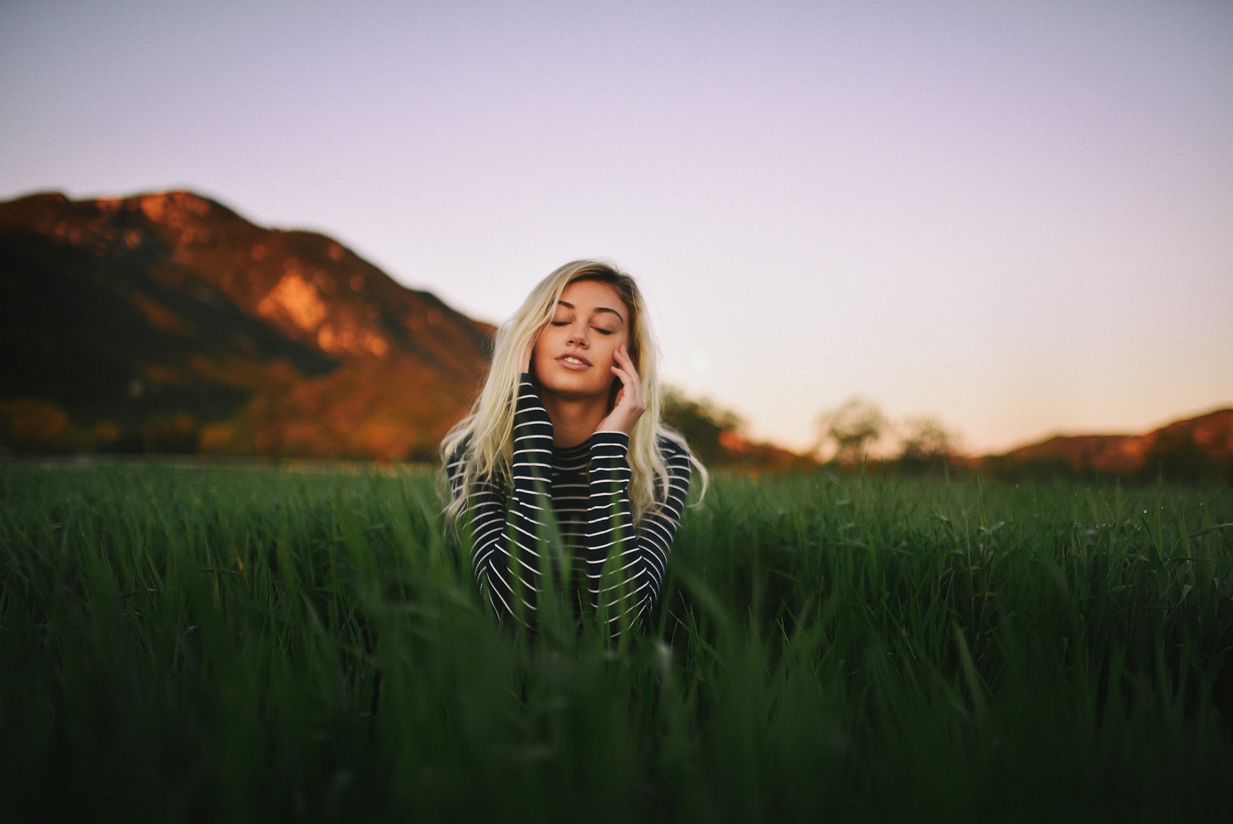 Woman with blonde hair sitting in a field HD Wallpaper