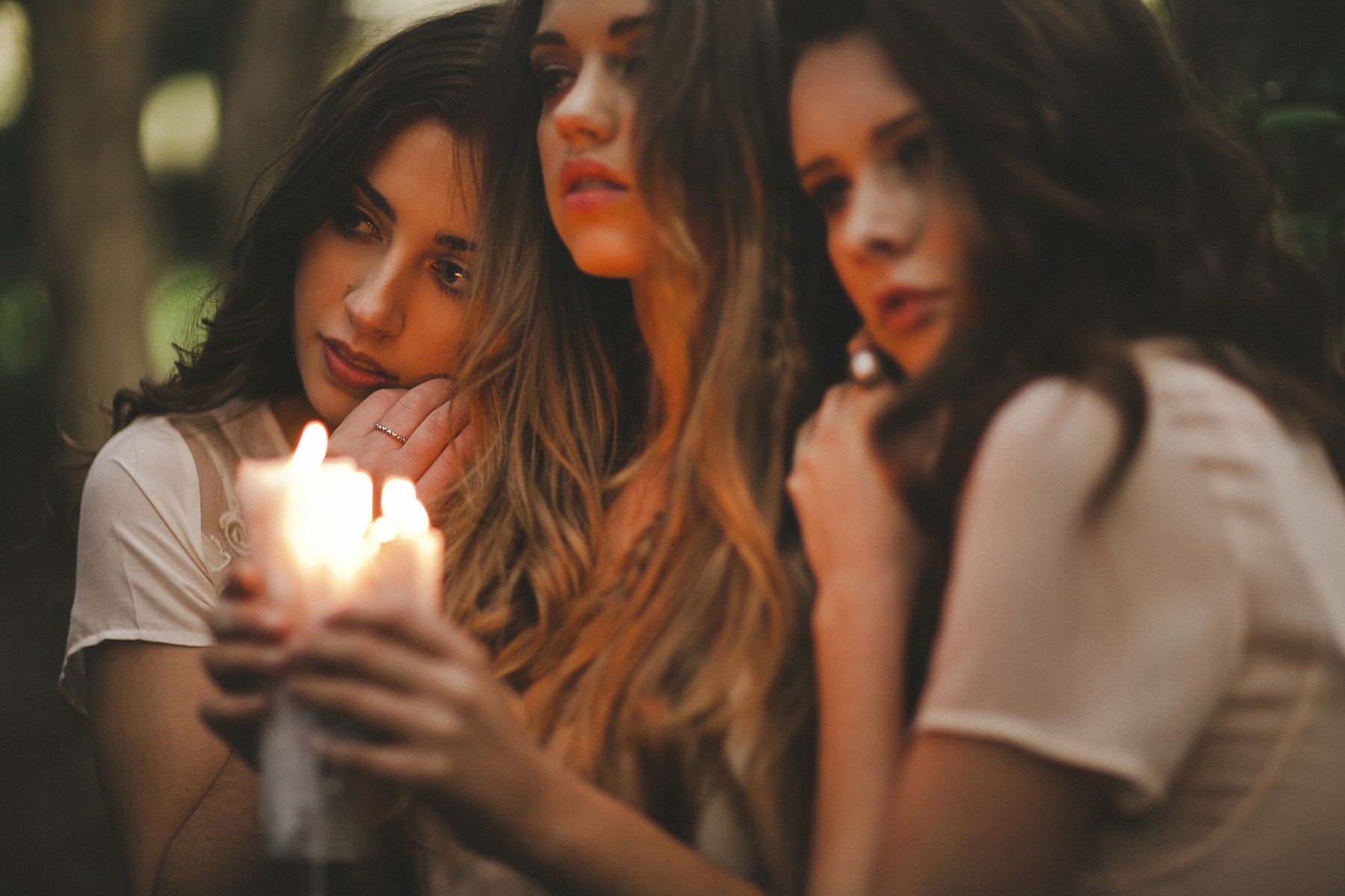 Three women holding candles in a forest HD Wallpaper