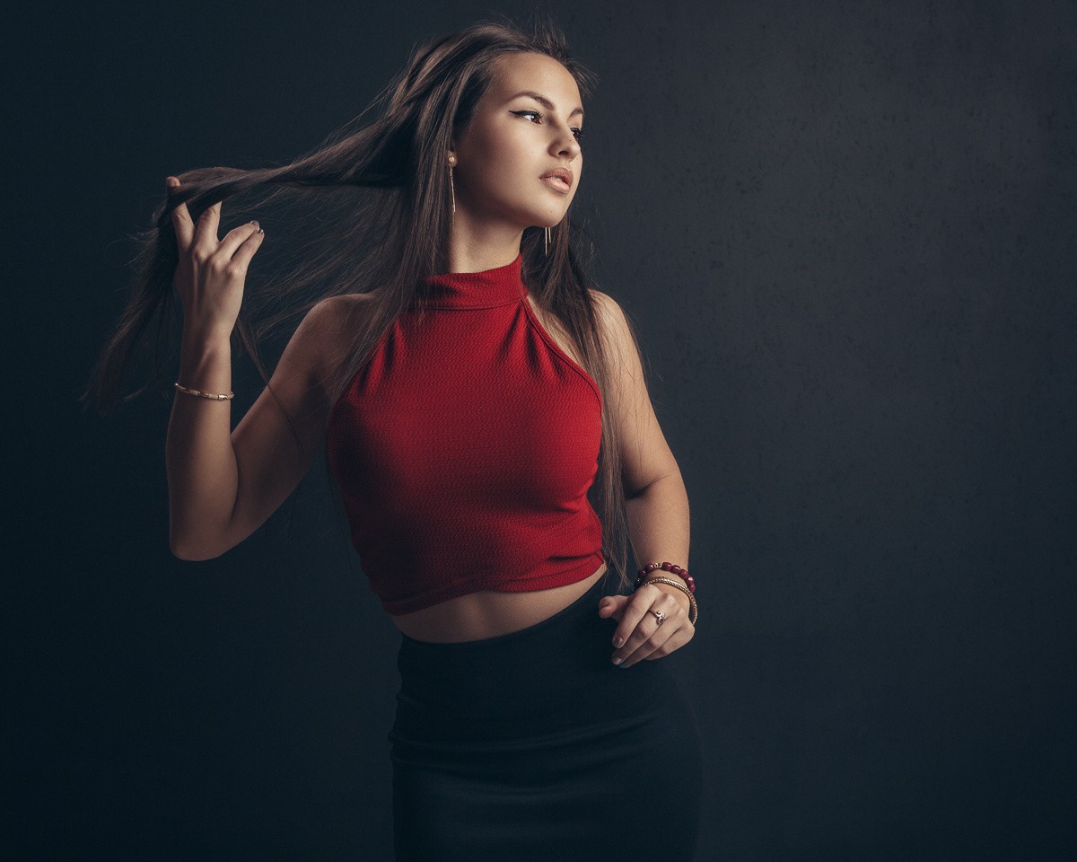 Woman in red top and black skirt with hands in hair HD Wallpaper