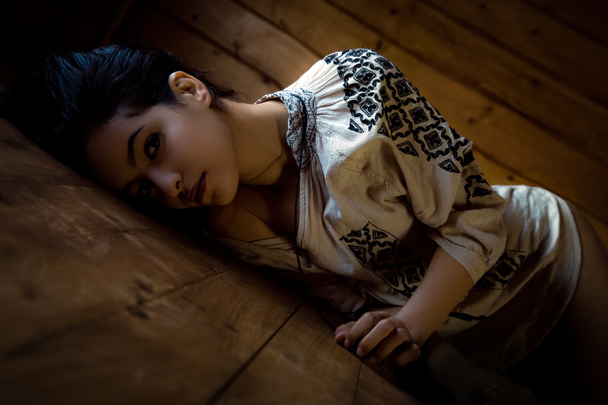 Woman with black hair lying on wooden floor HD Wallpaper