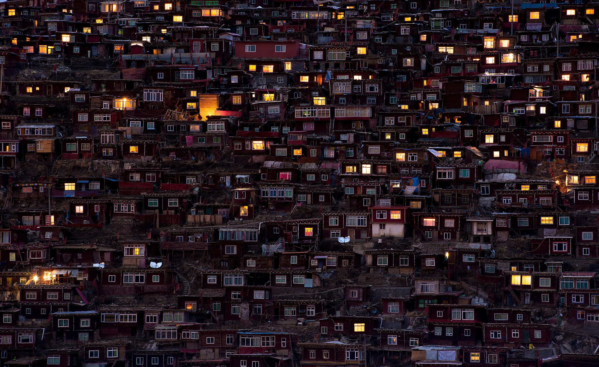 A hillside densely packed with illuminated houses at dusk HD Wallpaper