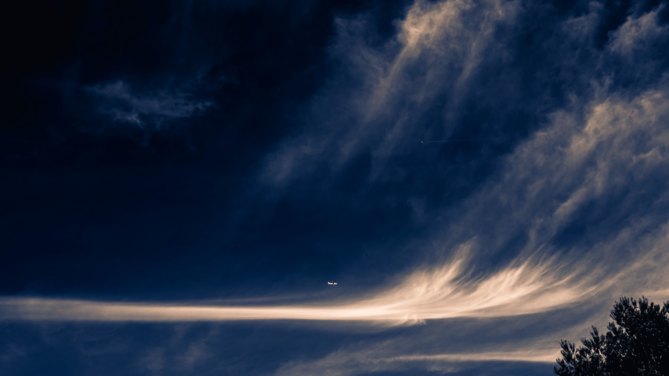 Airplane flying through dramatic clouds at dusk HD Wallpaper