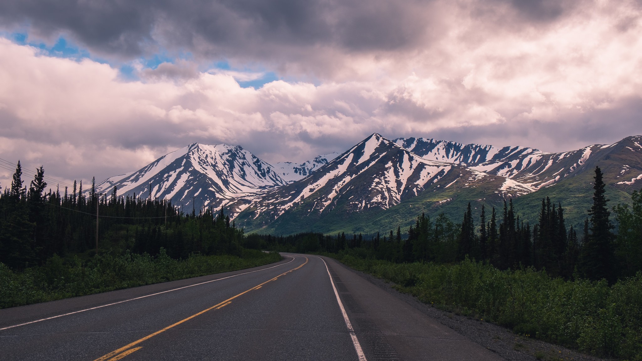 Road leading to snow-capped mountains under cloudy sky HD Wallpaper