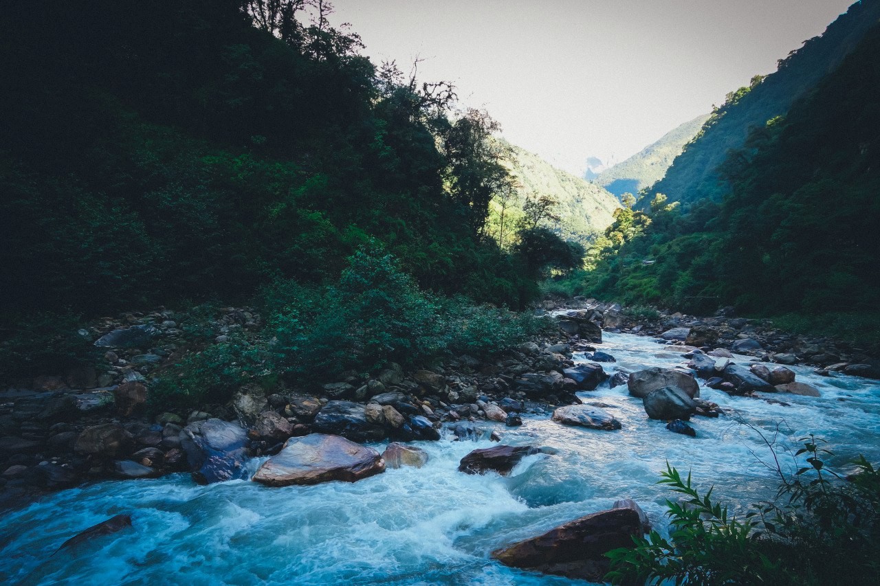 A river flows through a lush, green mountain valley. HD Wallpaper