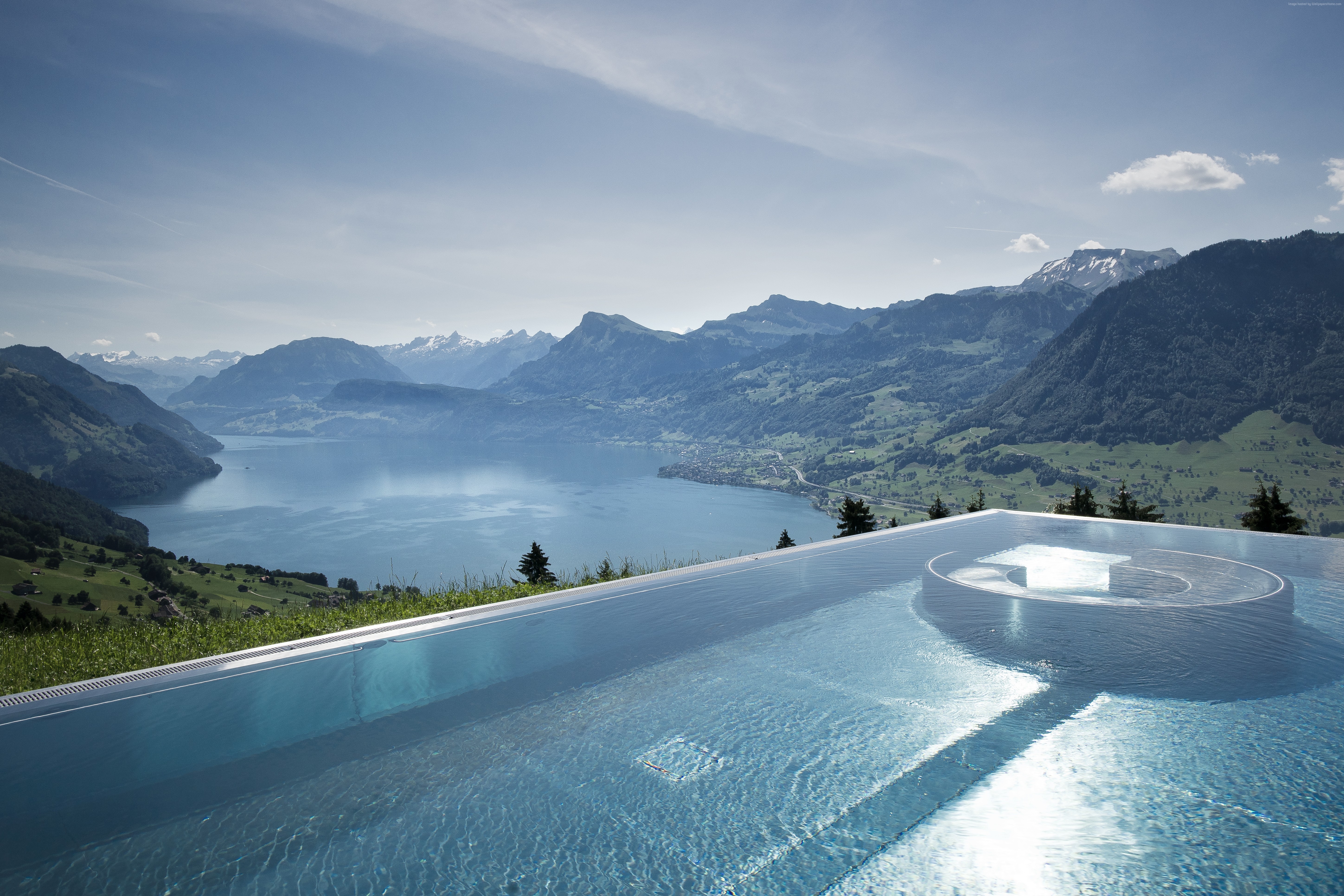 Infinity pool overlooking a lake and mountains HD Wallpaper