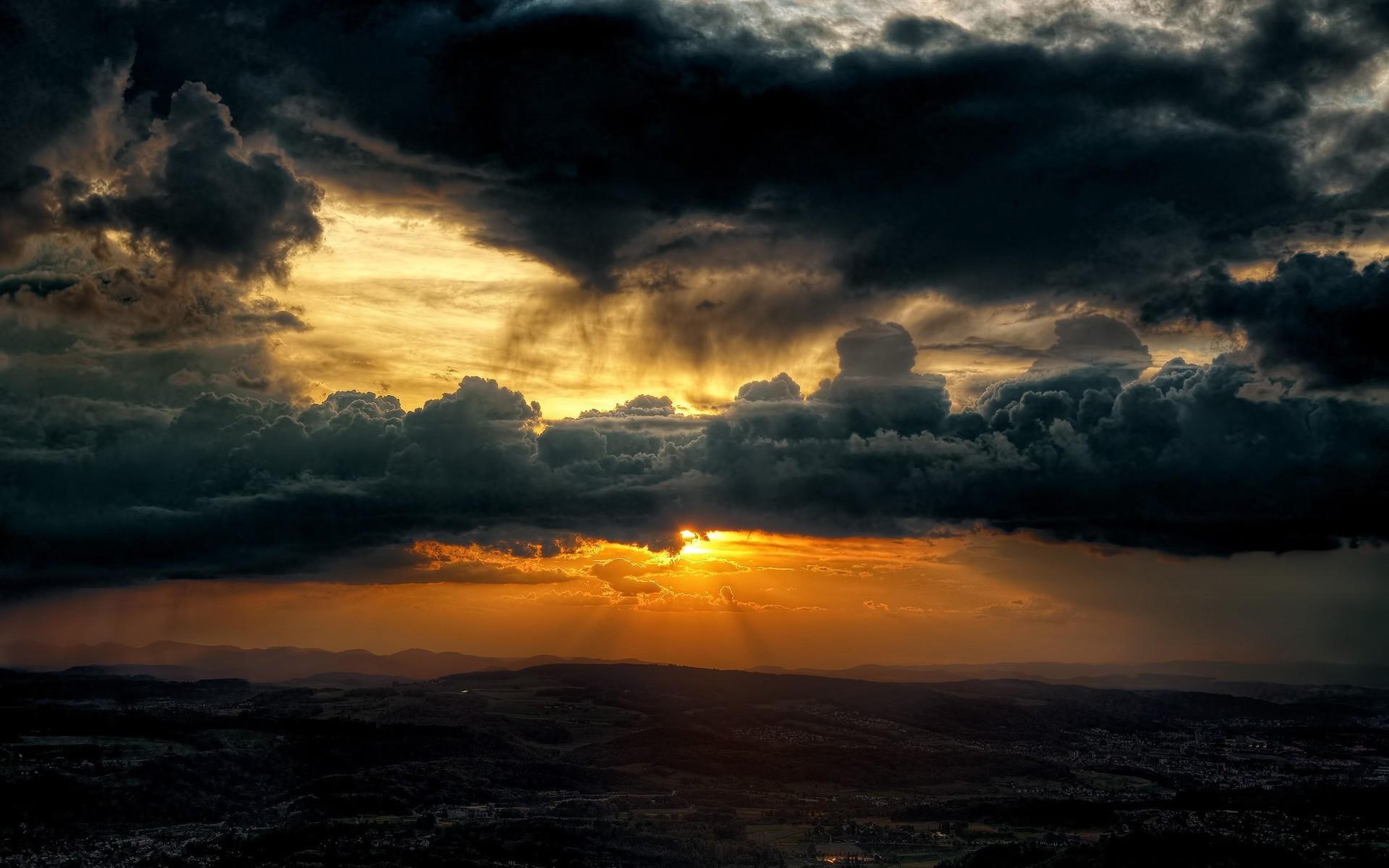 Dramatic sunset with dark storm clouds over mountains HD Wallpaper