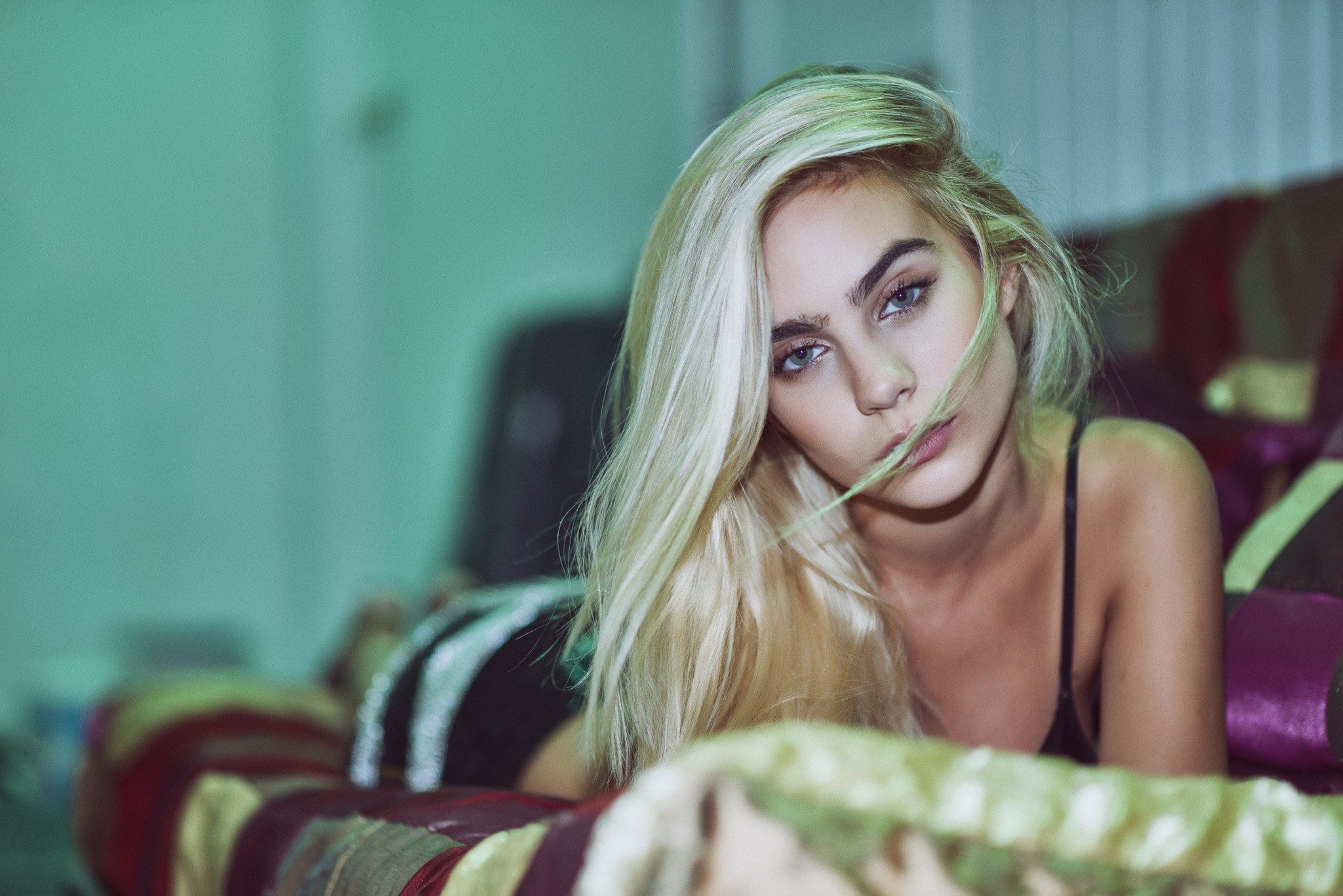 Blonde woman with blue eyes lying on a couch HD Wallpaper