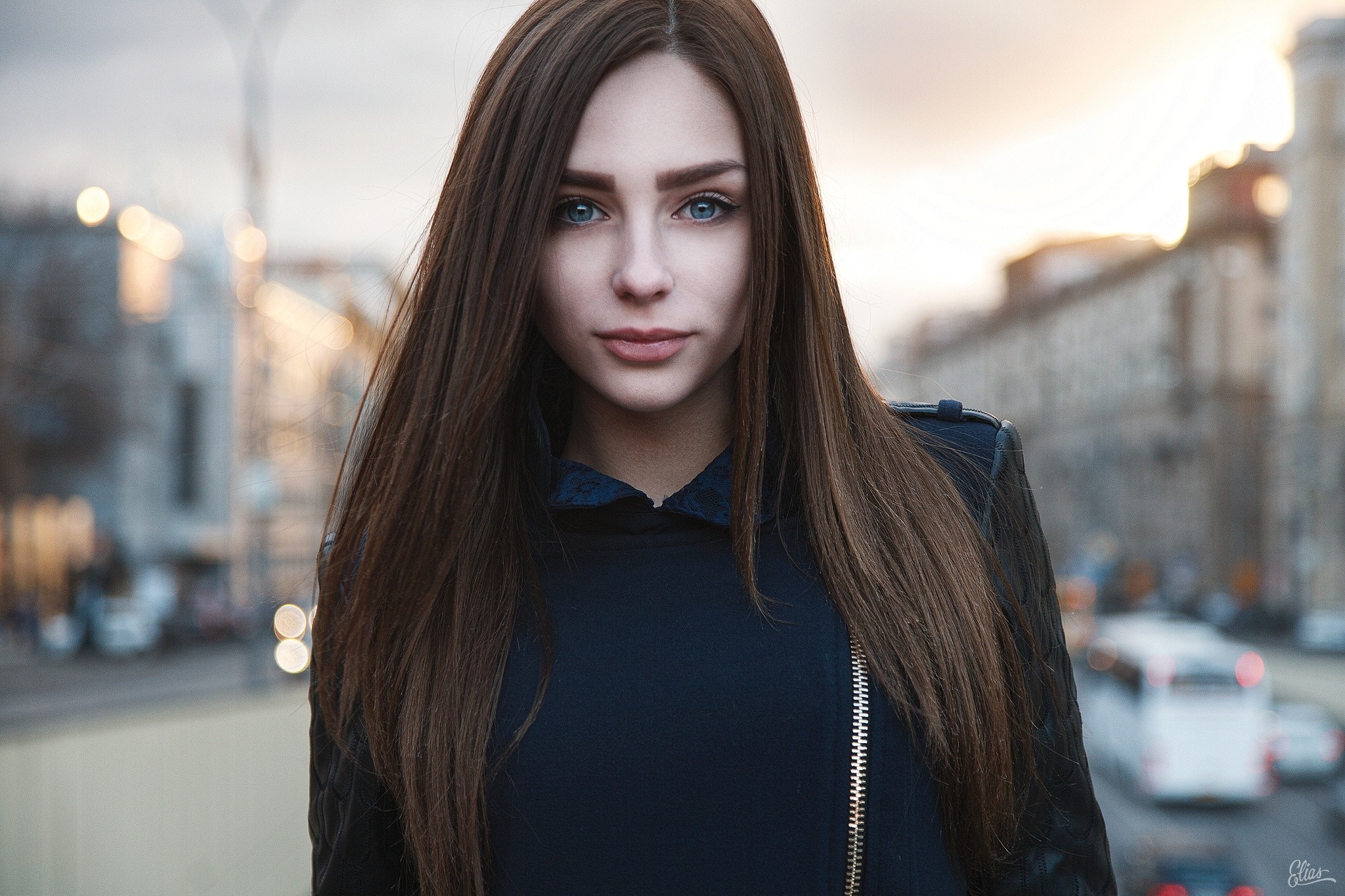 Woman with long brown hair and blue eyes in a city HD Wallpaper