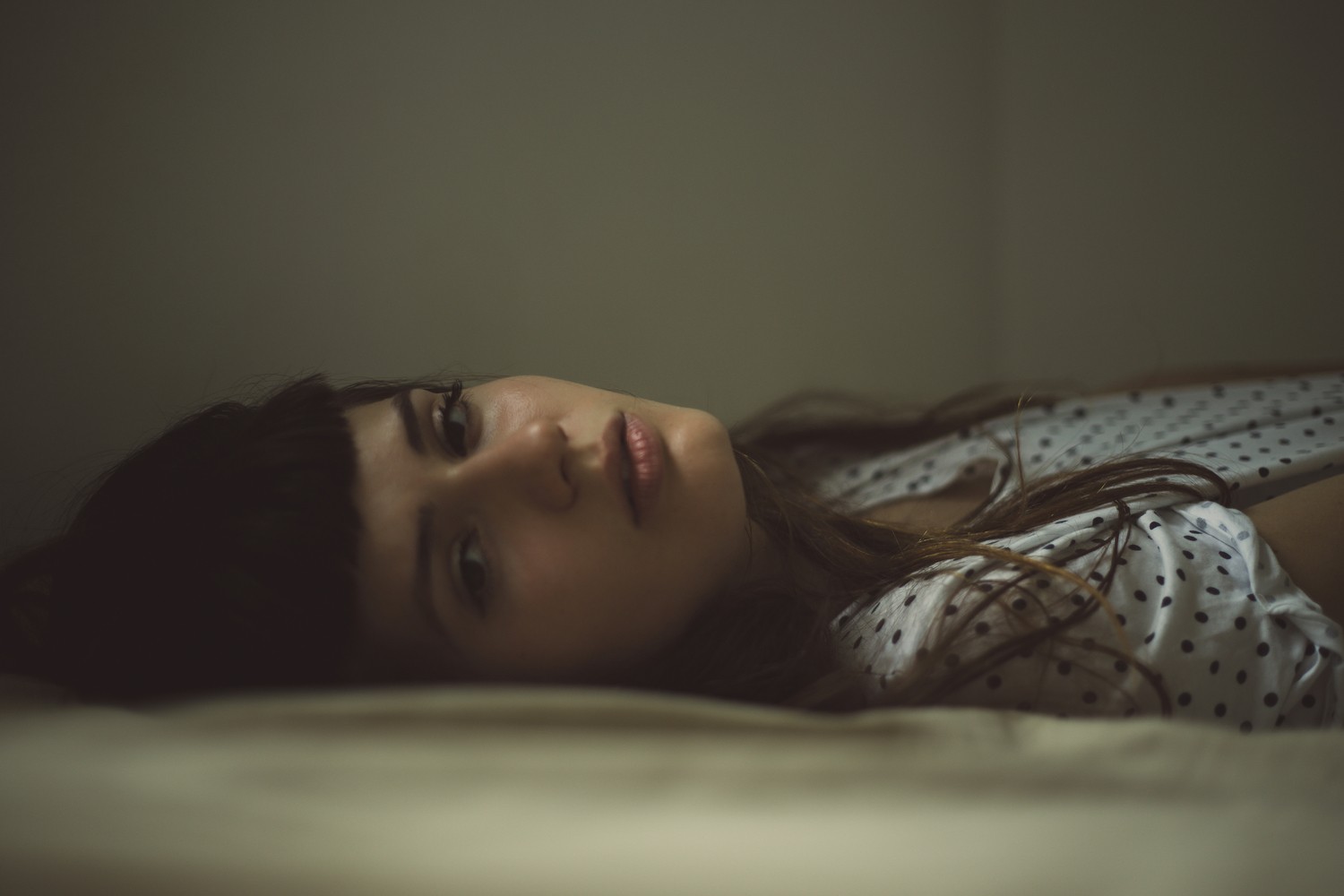 Woman with dark hair lying in bed HD Wallpaper