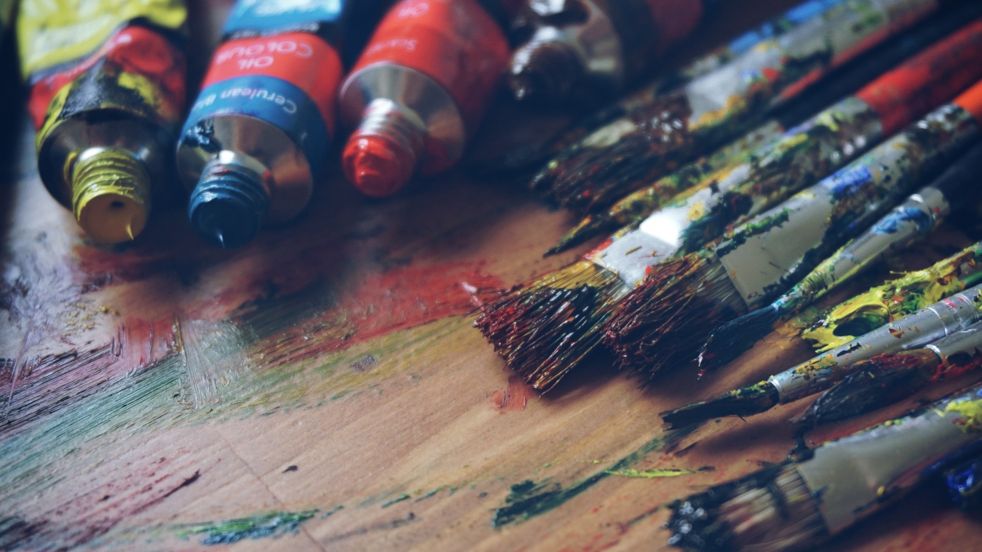 Paint tubes and paintbrushes on a colorful palette HD Wallpaper