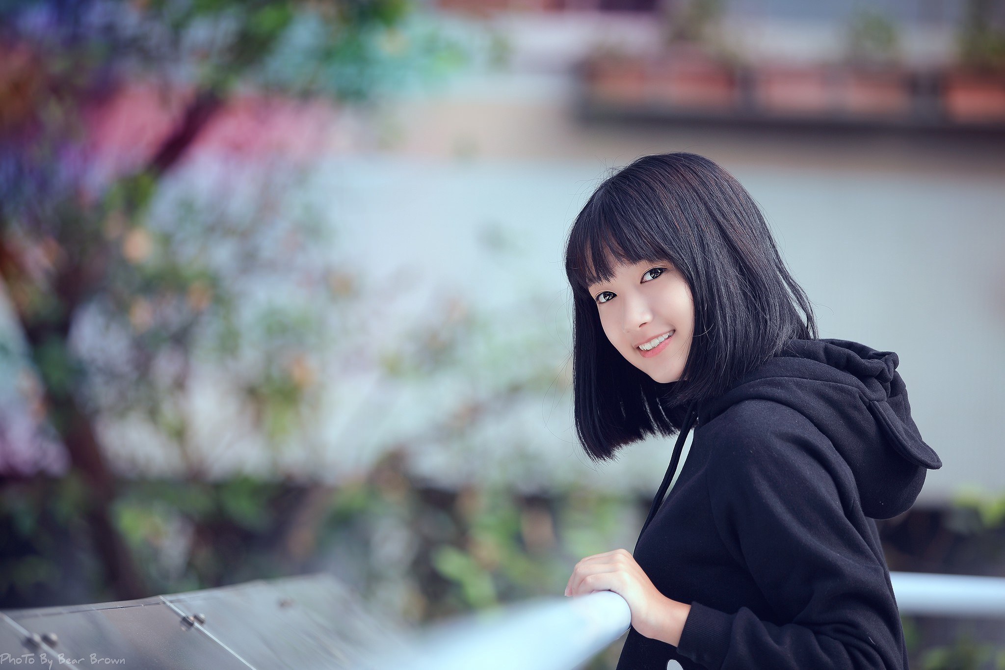 Young Asian woman in a black hoodie smiling HD Wallpaper