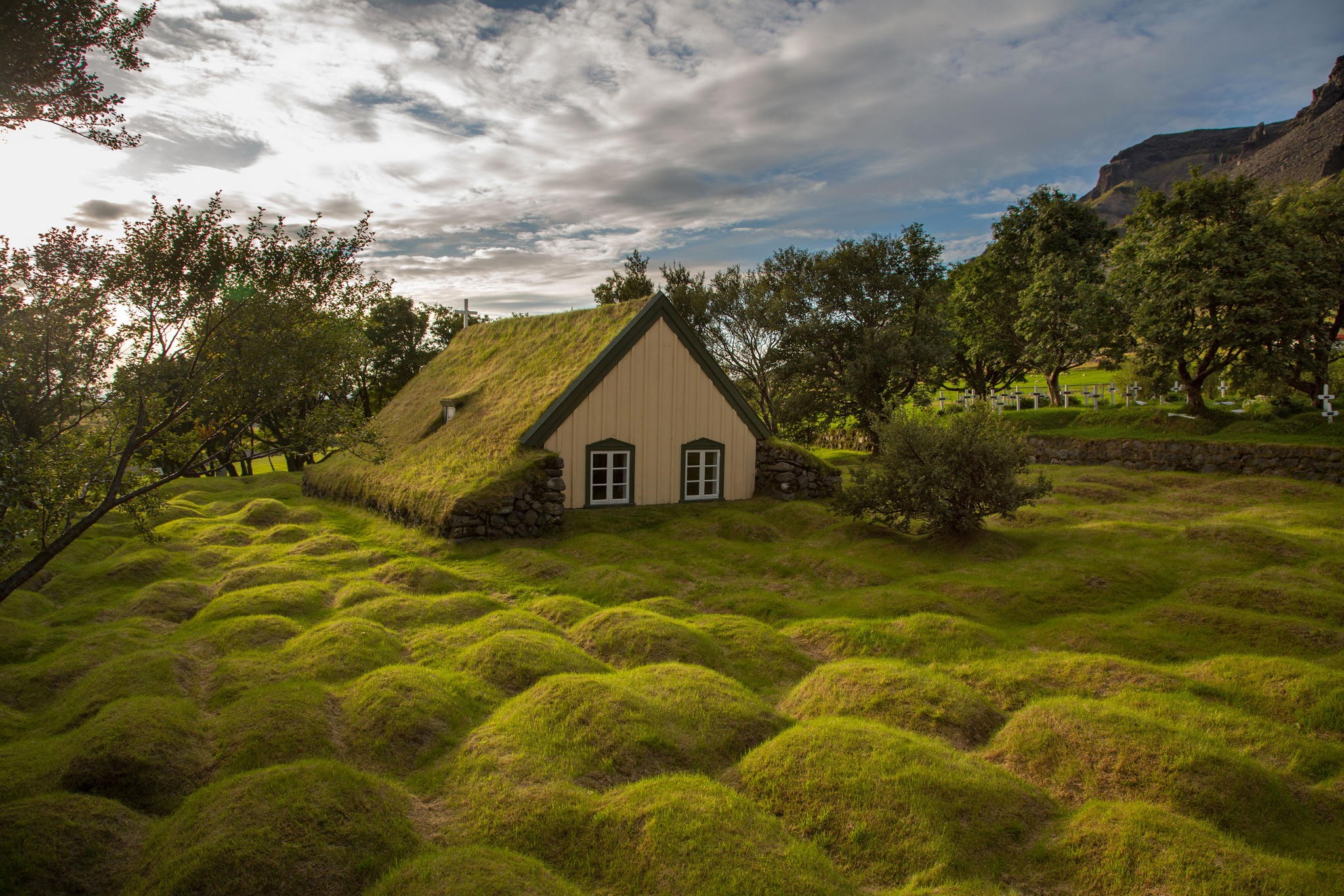 Grass-roofed house in a hilly green landscape in Iceland HD Wallpaper