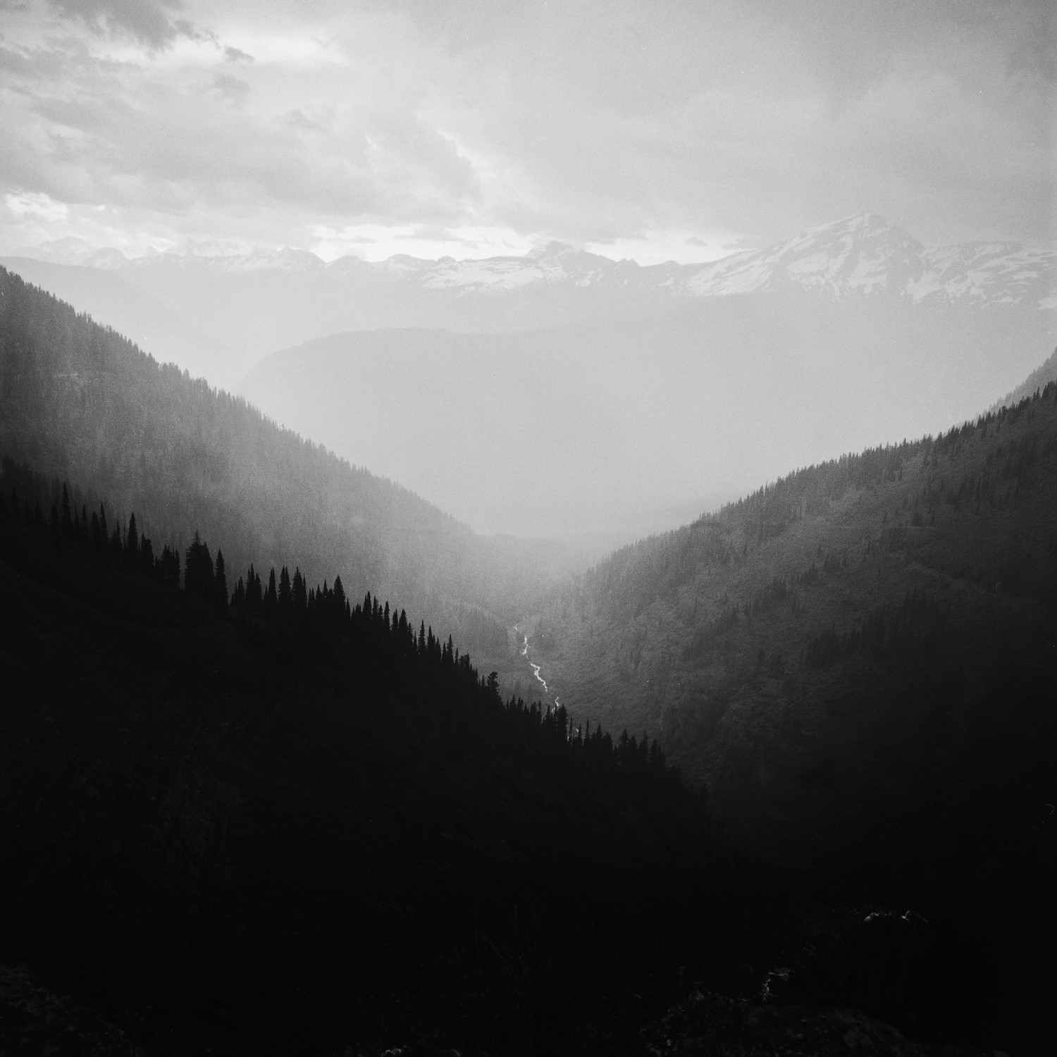Misty mountain valley with a river and snow-capped peaks HD Wallpaper