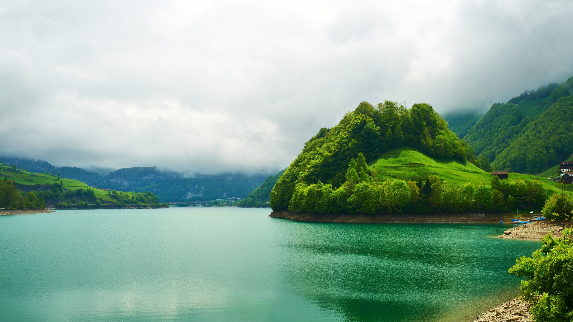 Turquoise lake surrounded by green hills and mountains HD Wallpaper