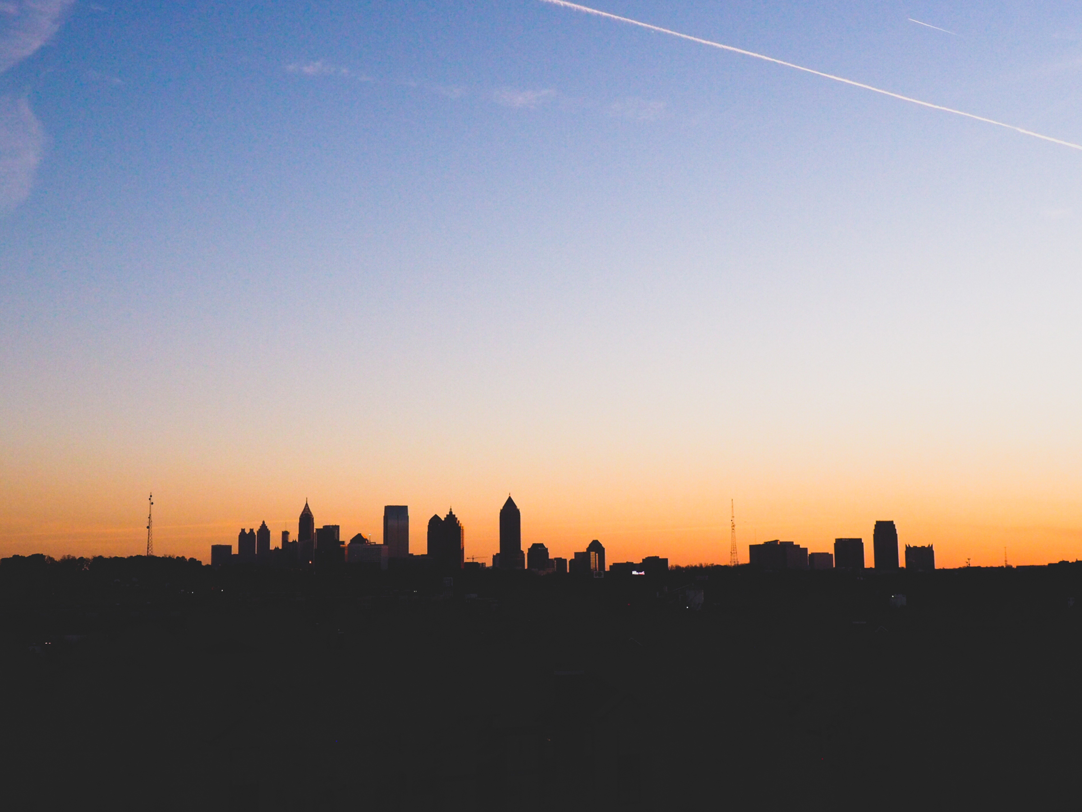 City skyline at sunset with contrails HD Wallpaper