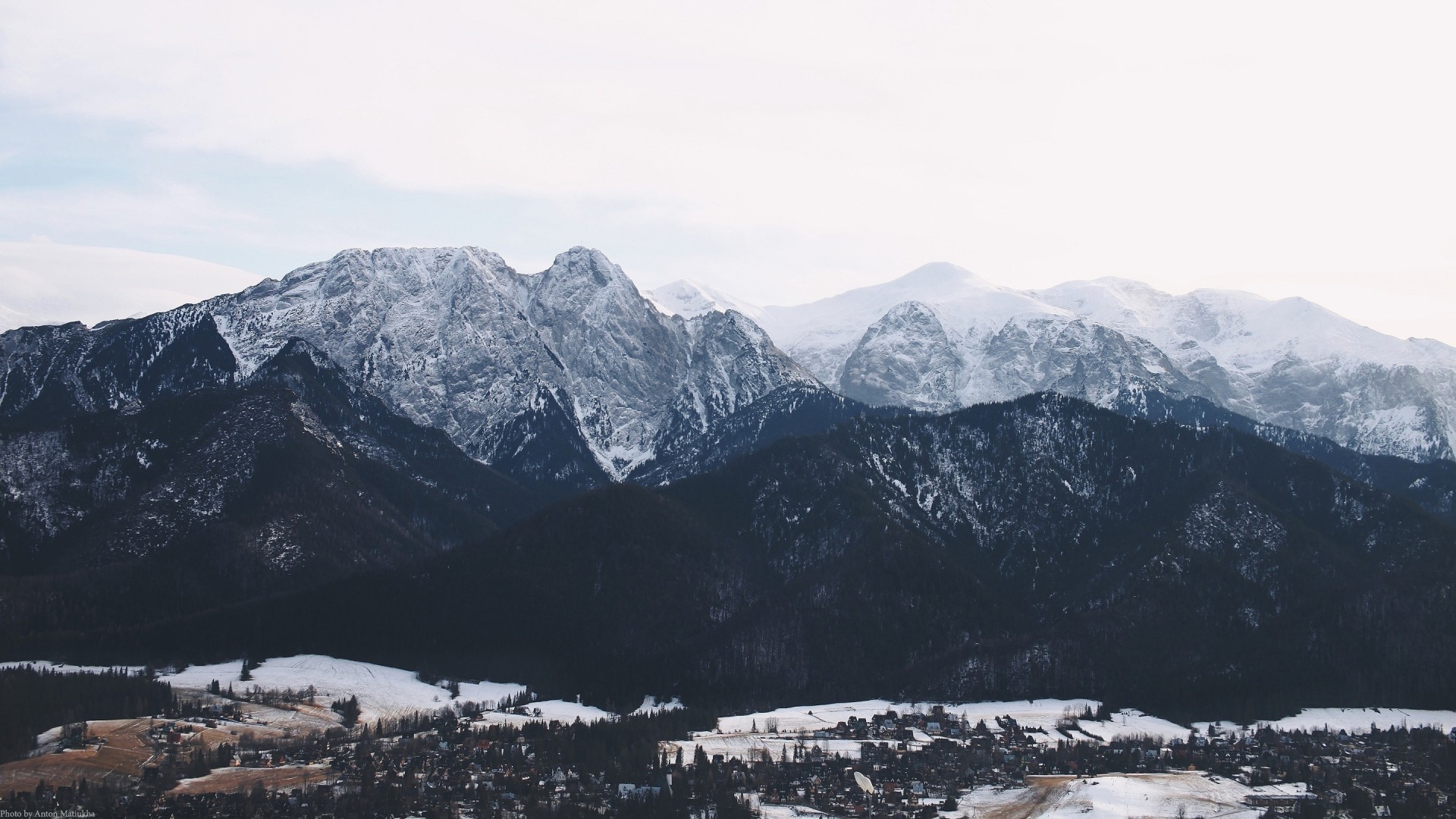 Snow-covered mountains above a village HD Wallpaper
