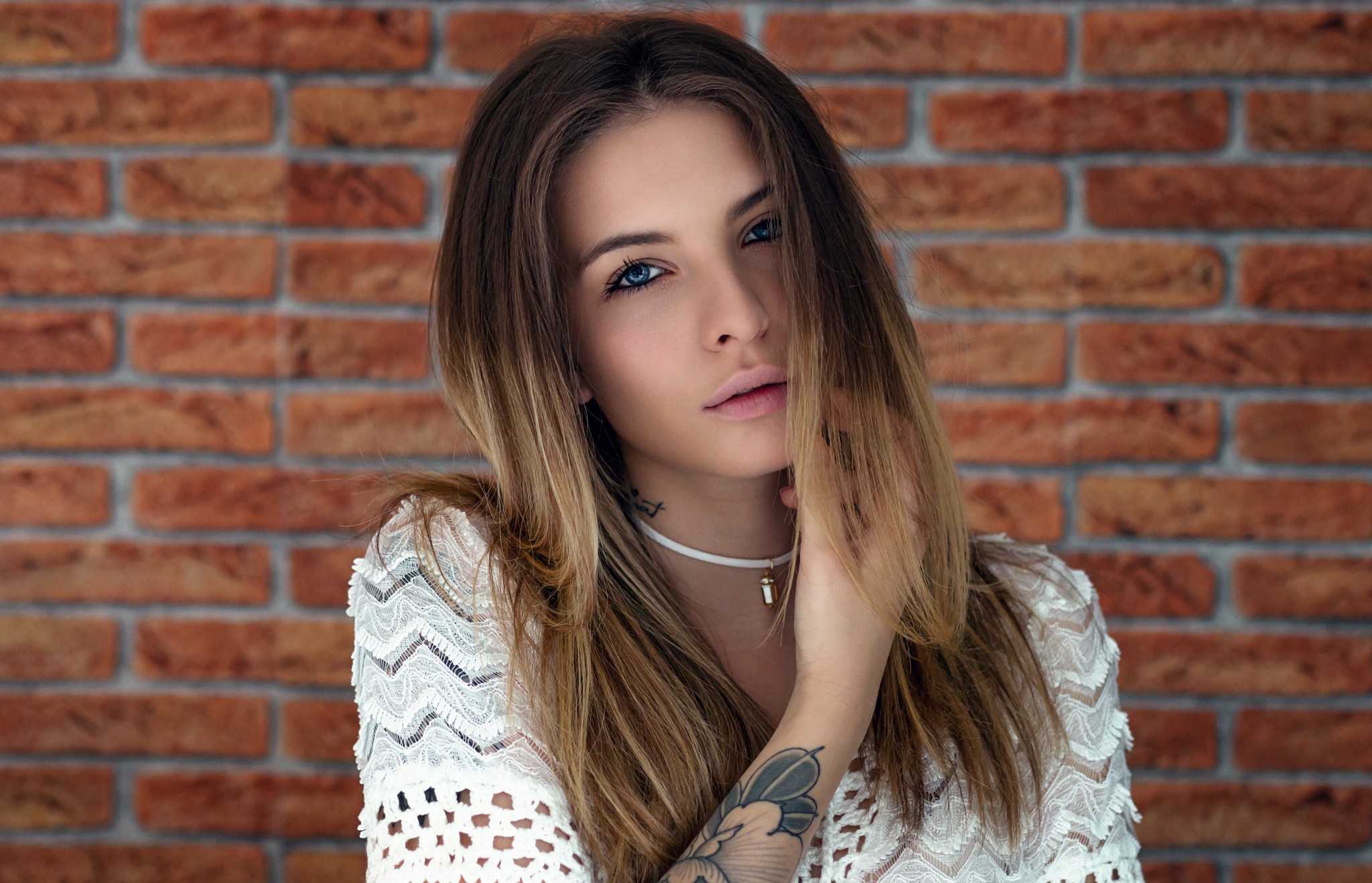 Woman with tattoos in front of a brick wall HD Wallpaper