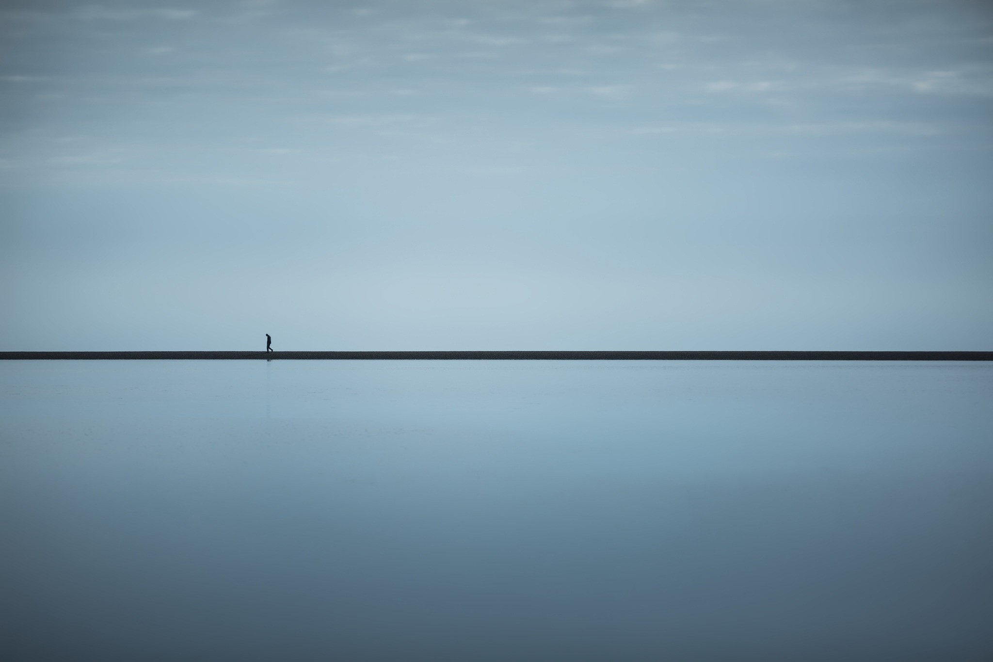A lone figure walks on a thin line across water HD Wallpaper