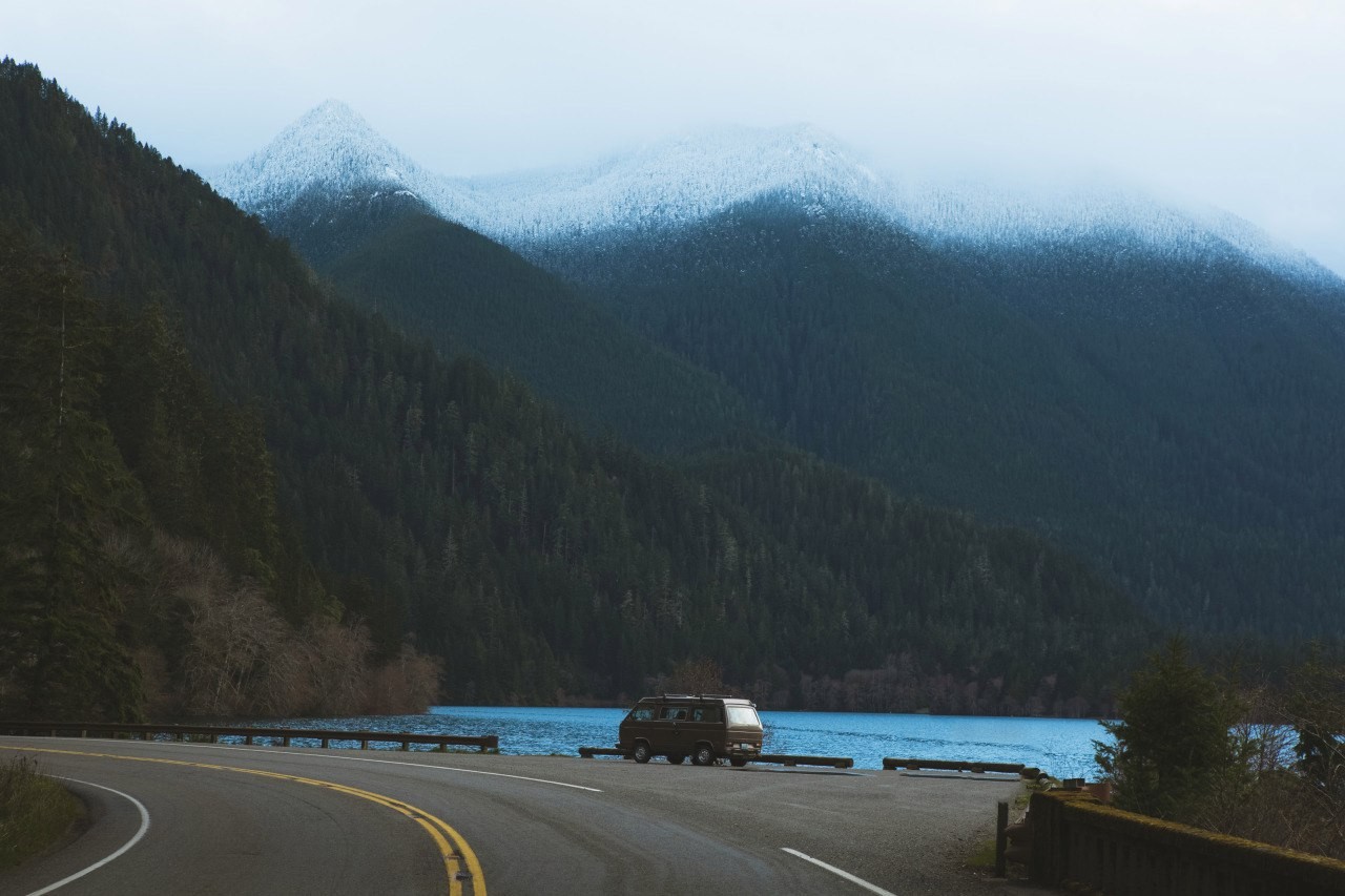 Van parked by a lake with snow-capped mountains HD Wallpaper
