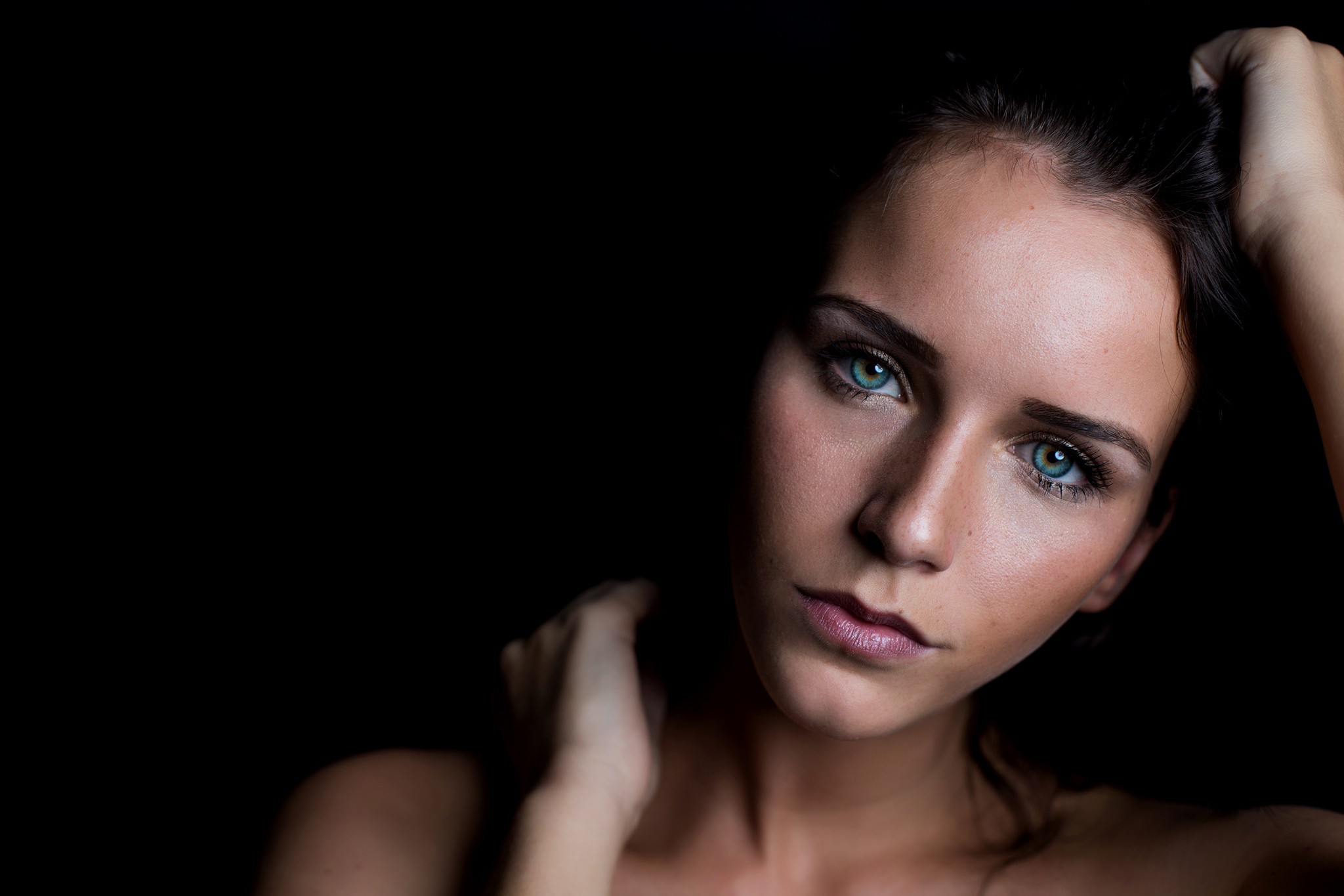 Woman with striking blue eyes against a black background HD Wallpaper