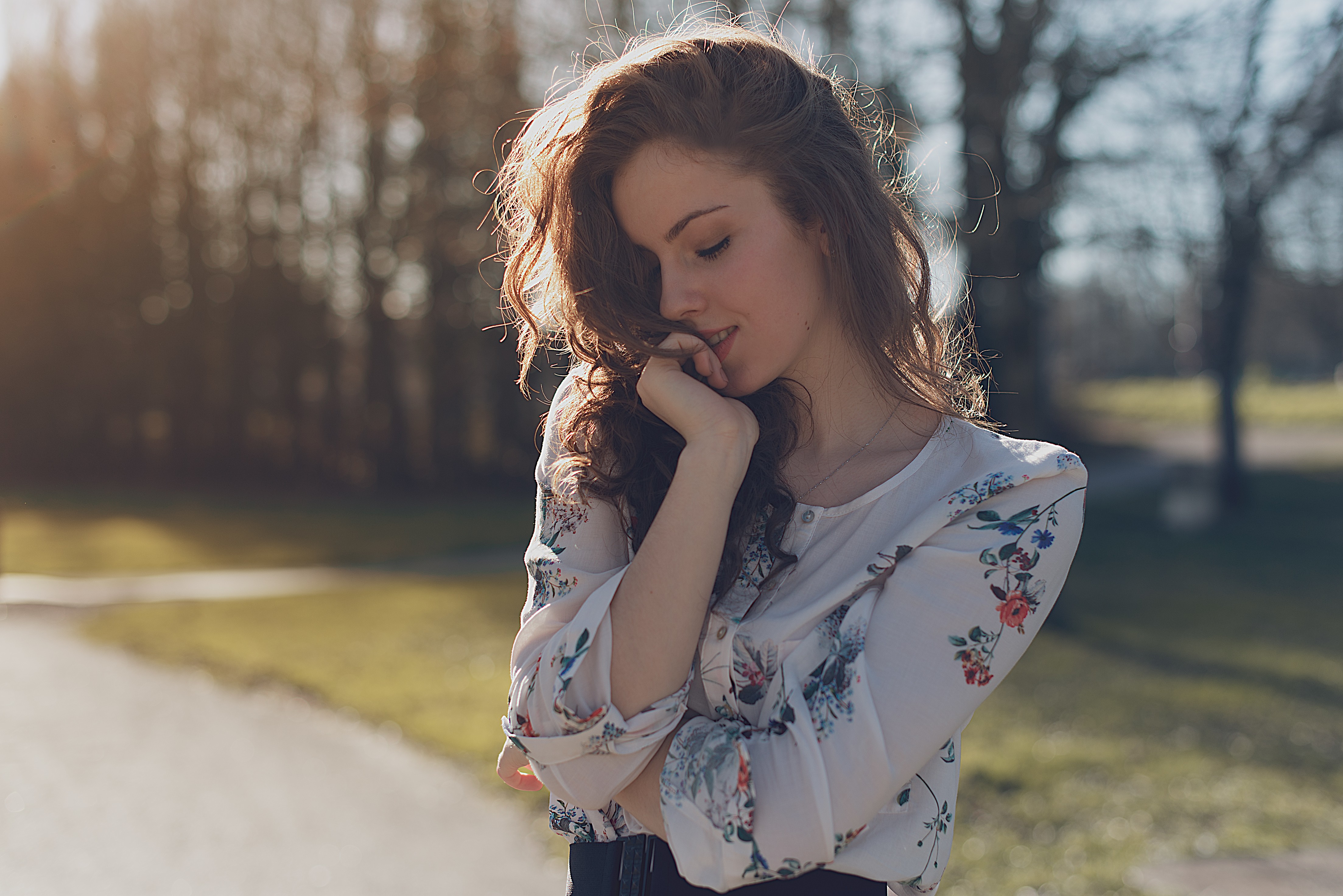 Woman with long wavy hair in a floral shirt outdoors HD Wallpaper
