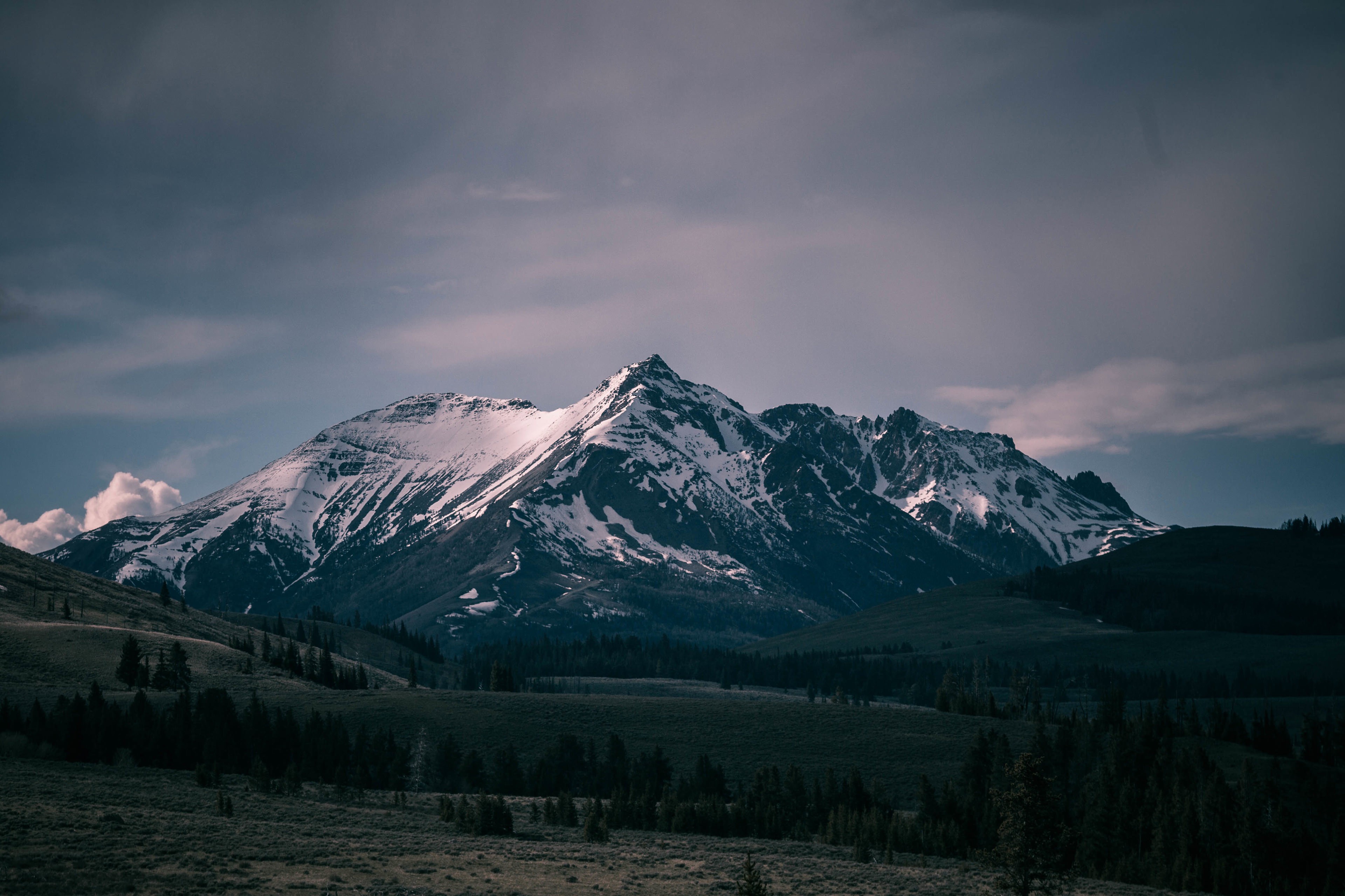 Snow-capped mountains under a cloudy sky HD Wallpaper