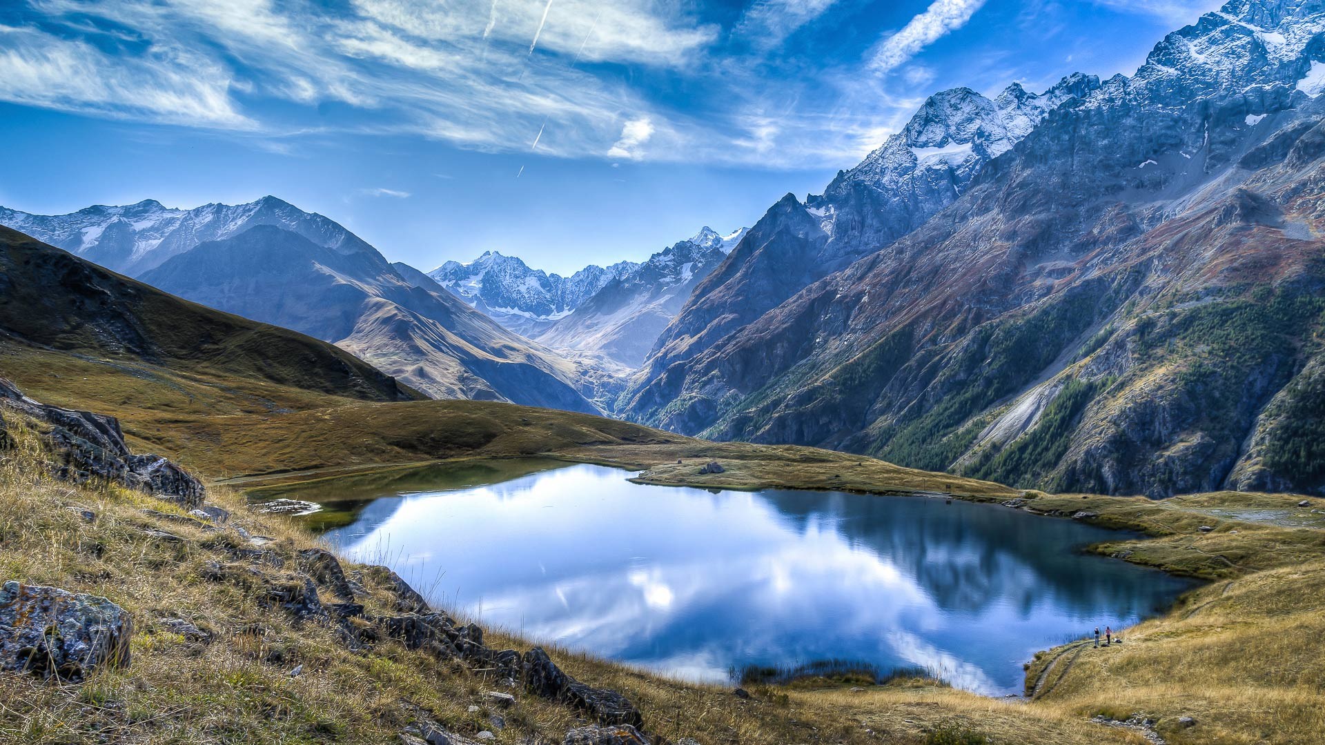 Mountain lake reflecting snow-capped peaks under a blue sky HD Wallpaper