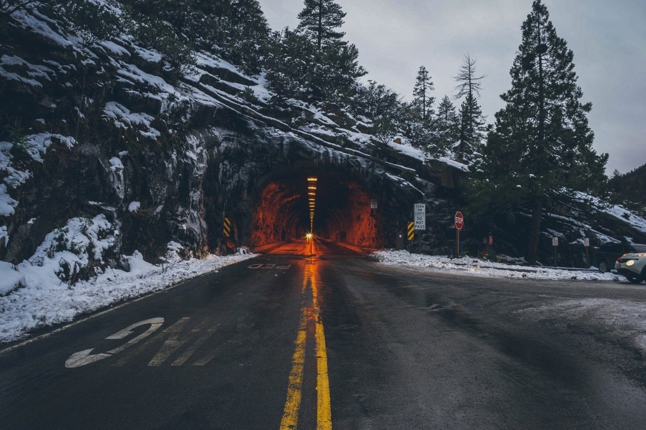 Snowy mountain road leading to a tunnel HD Wallpaper