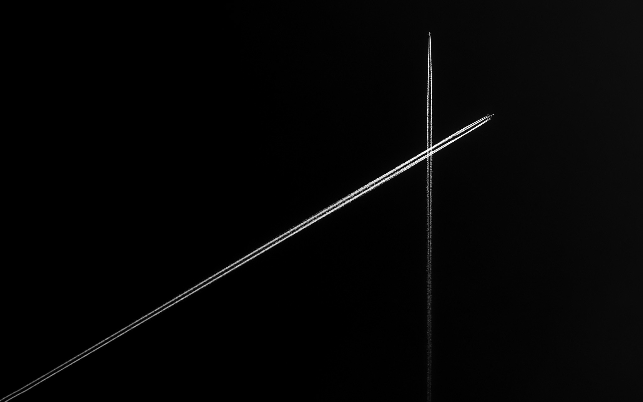 Abstract black and white image of airplane contrails crossing HD Wallpaper