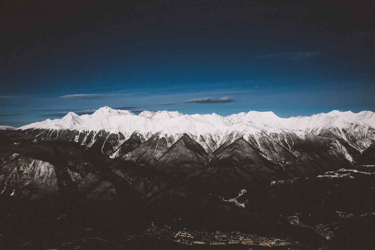 Snow-capped mountains under a dark blue sky HD Wallpaper