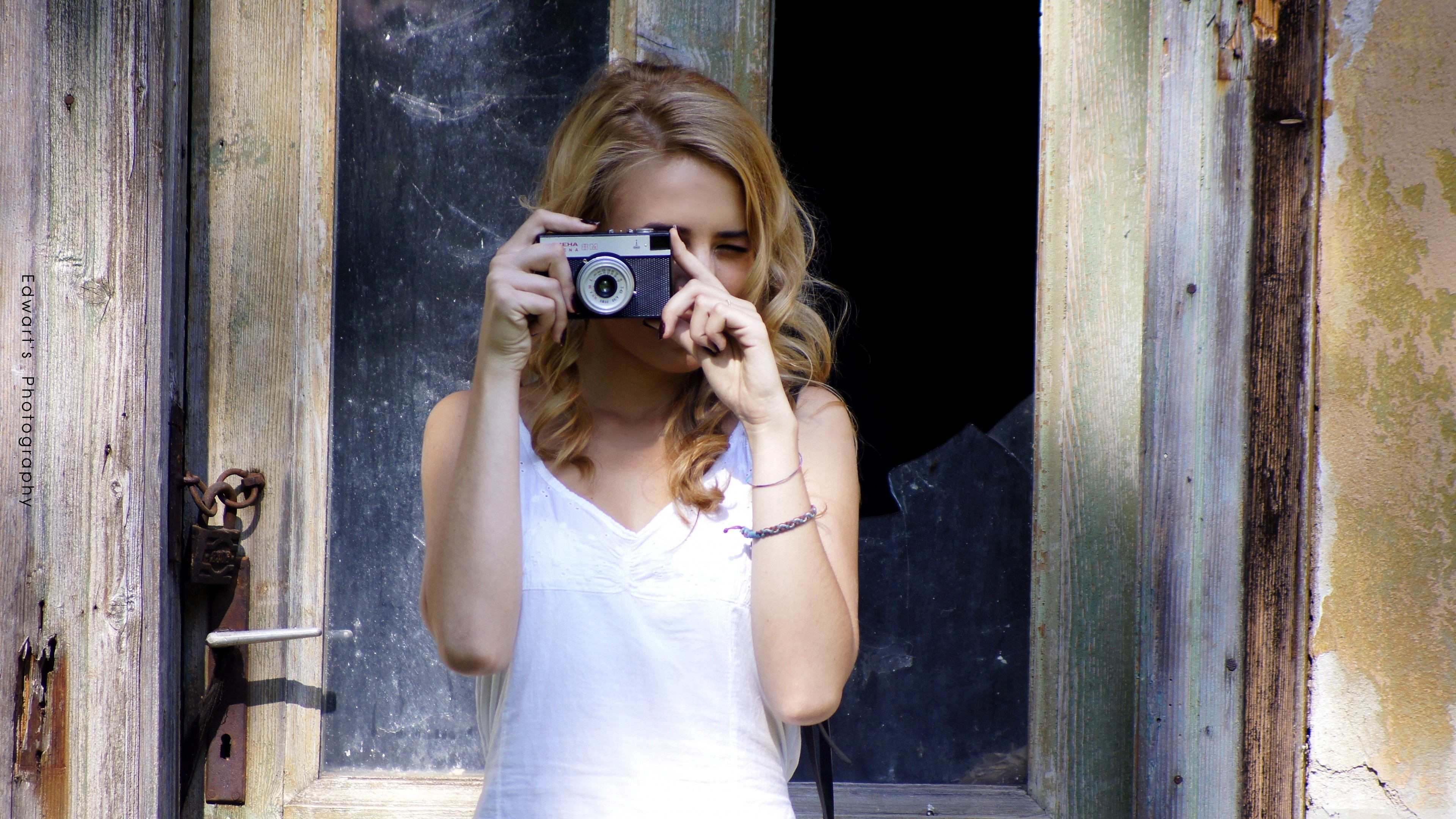 Woman holding a vintage camera in a doorway HD Wallpaper