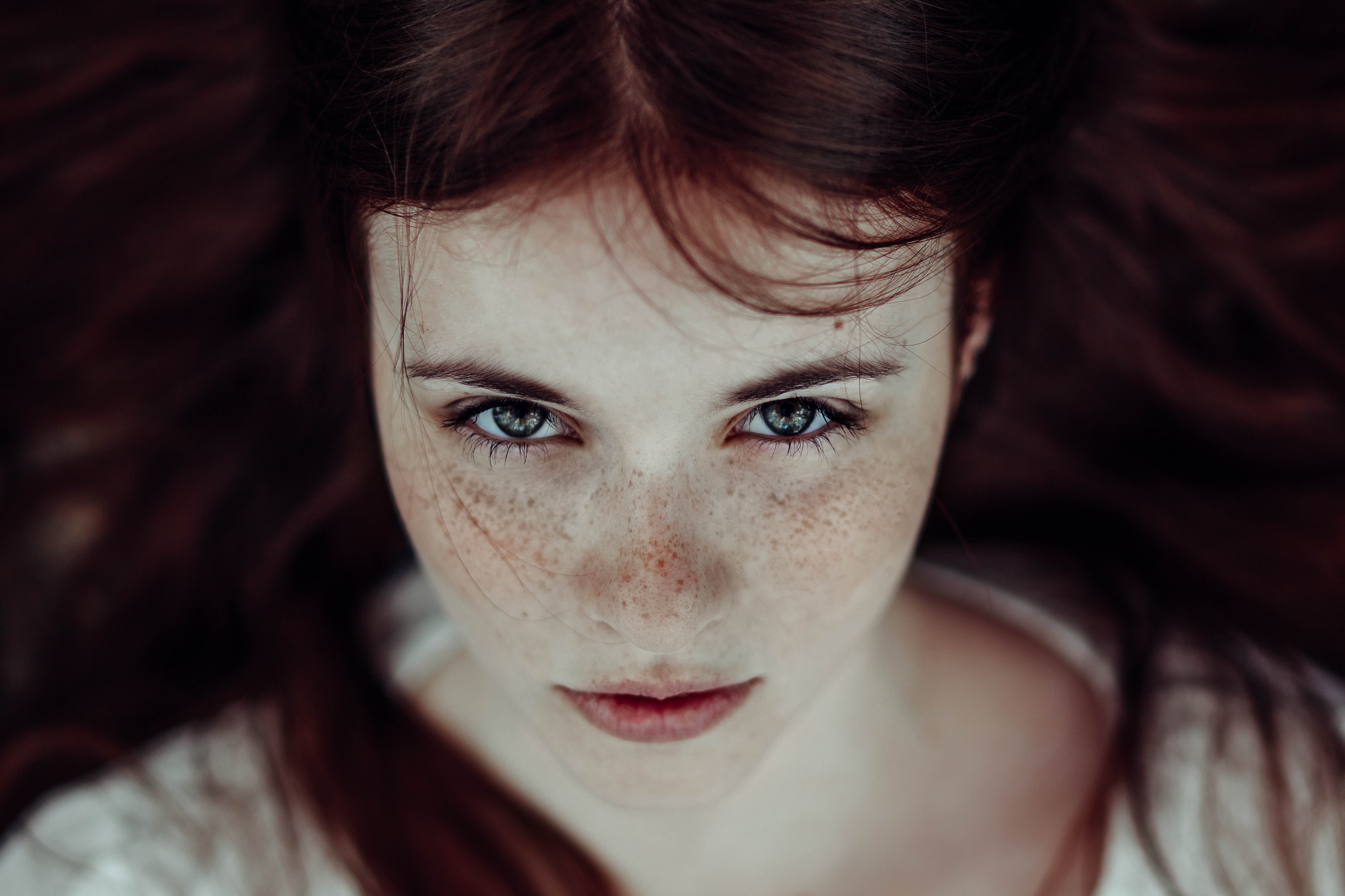 Young woman with freckles looking at viewer HD Wallpaper