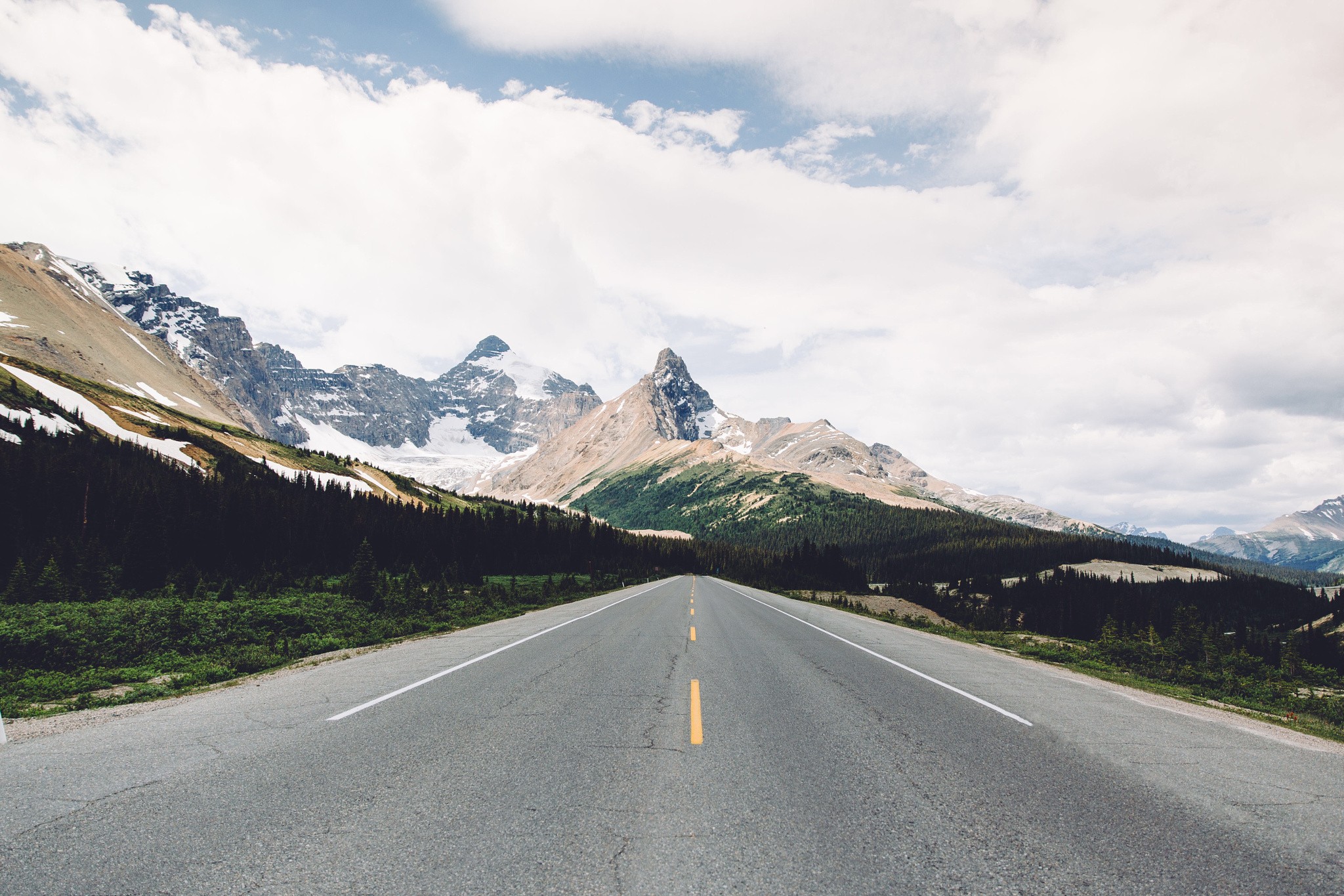 Road leading to snow-capped mountains HD Wallpaper