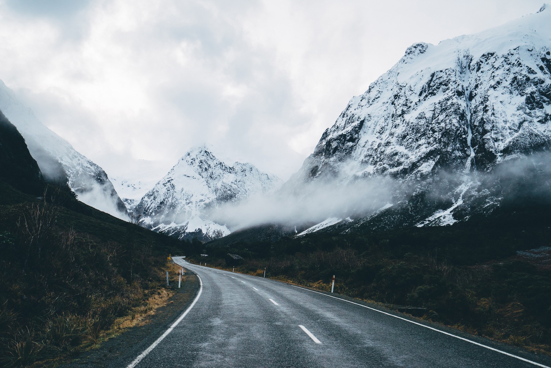 A winding road through snow-capped mountains HD Wallpaper