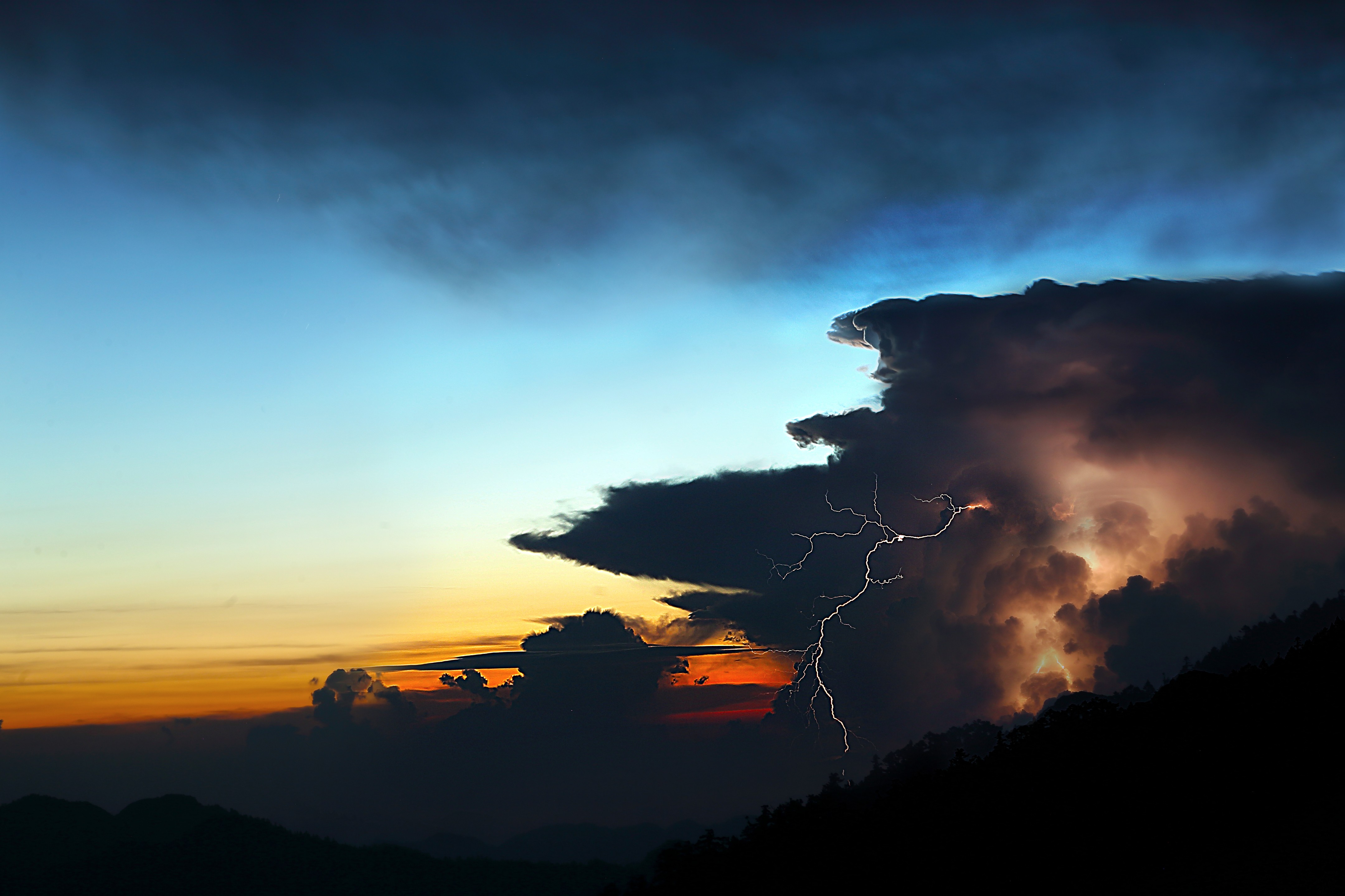 Lightning strikes through dark storm clouds at sunset HD Wallpaper