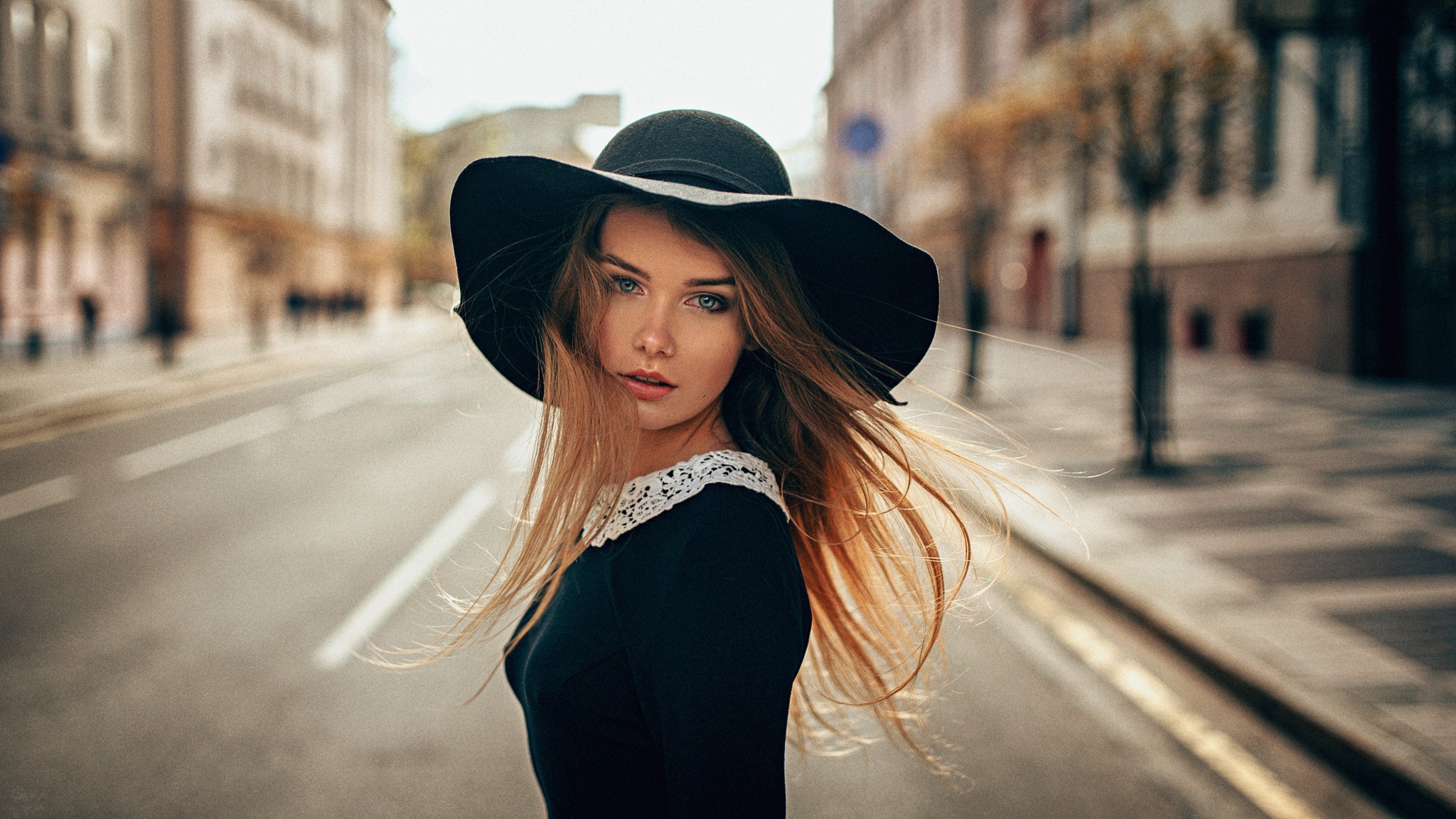 Woman in a black hat and dress on a city street HD Wallpaper