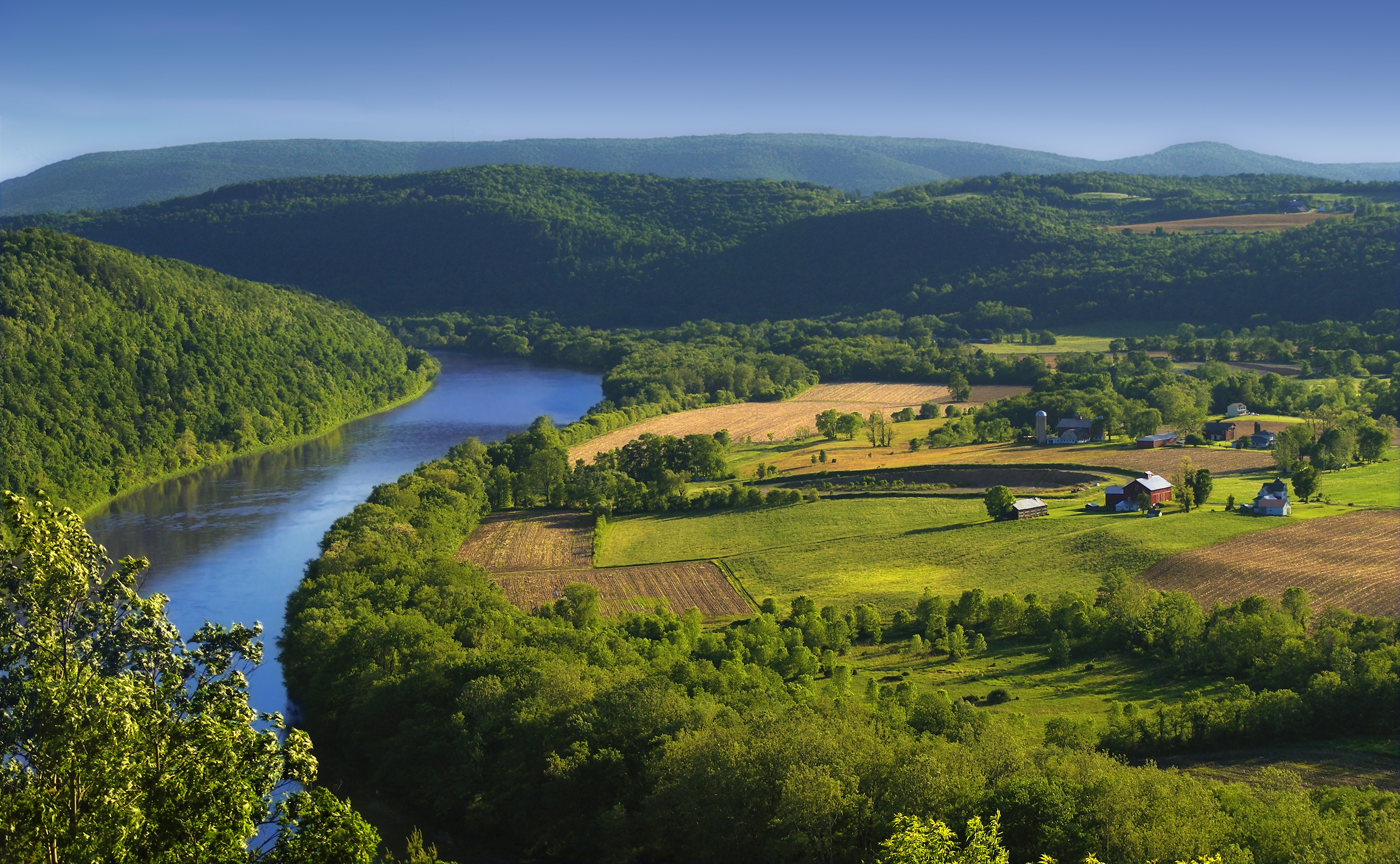 River valley with farms and rolling green hills HD Wallpaper
