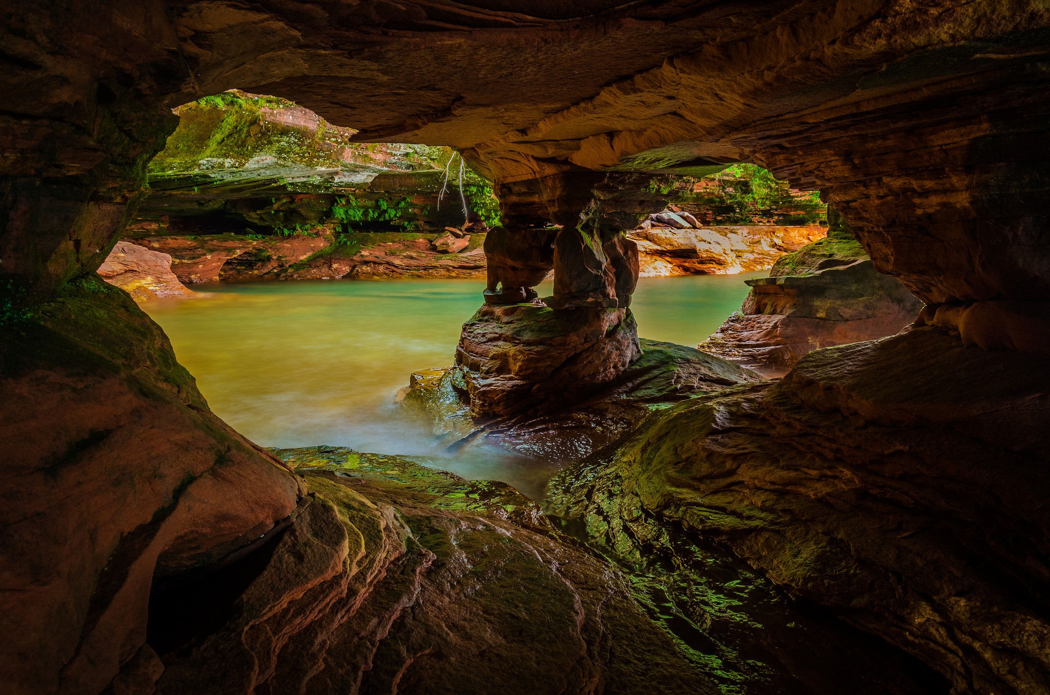 Cave opening with water and rock formations HD Wallpaper