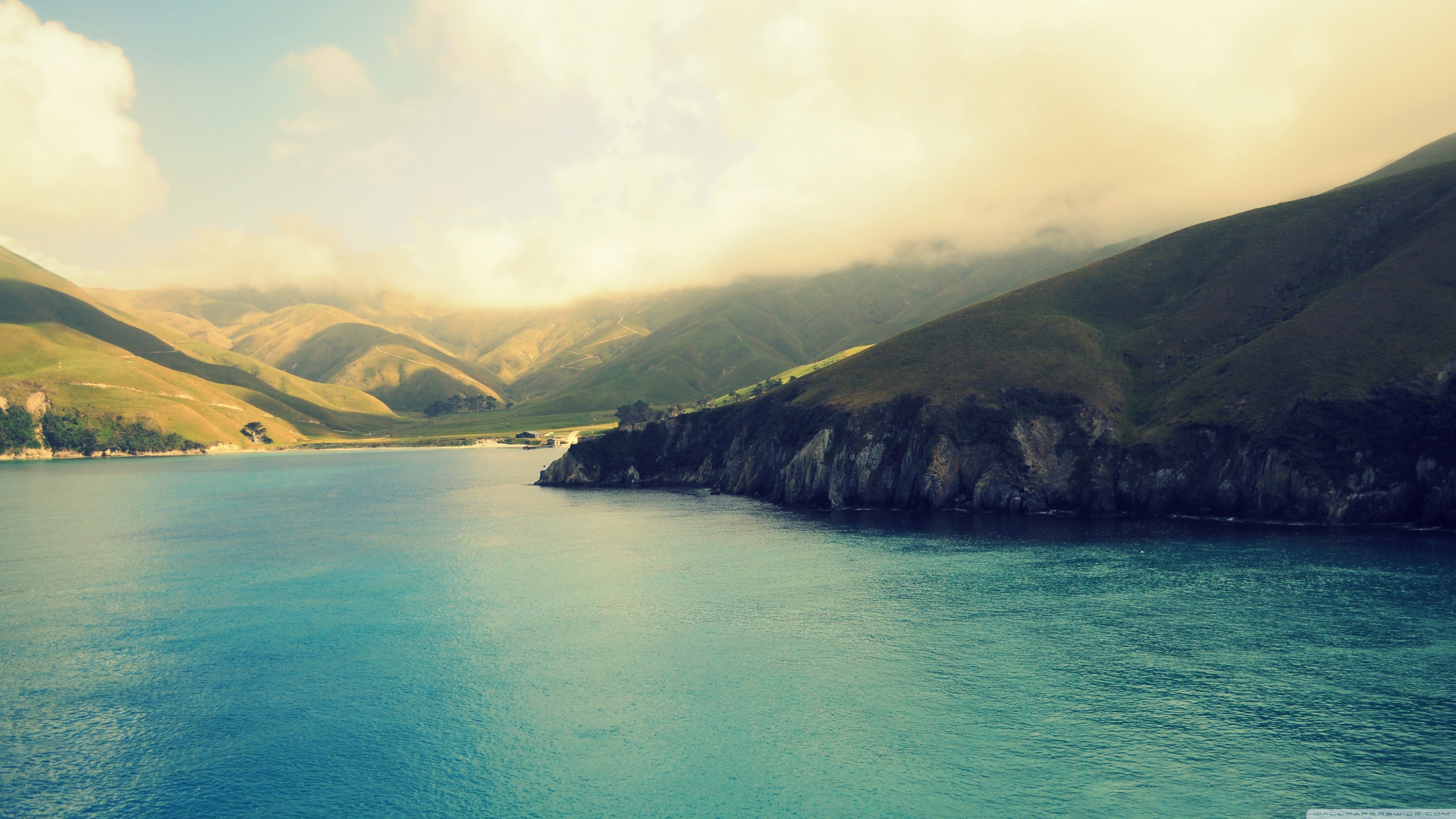 Turquoise bay surrounded by green hills and cliffs HD Wallpaper