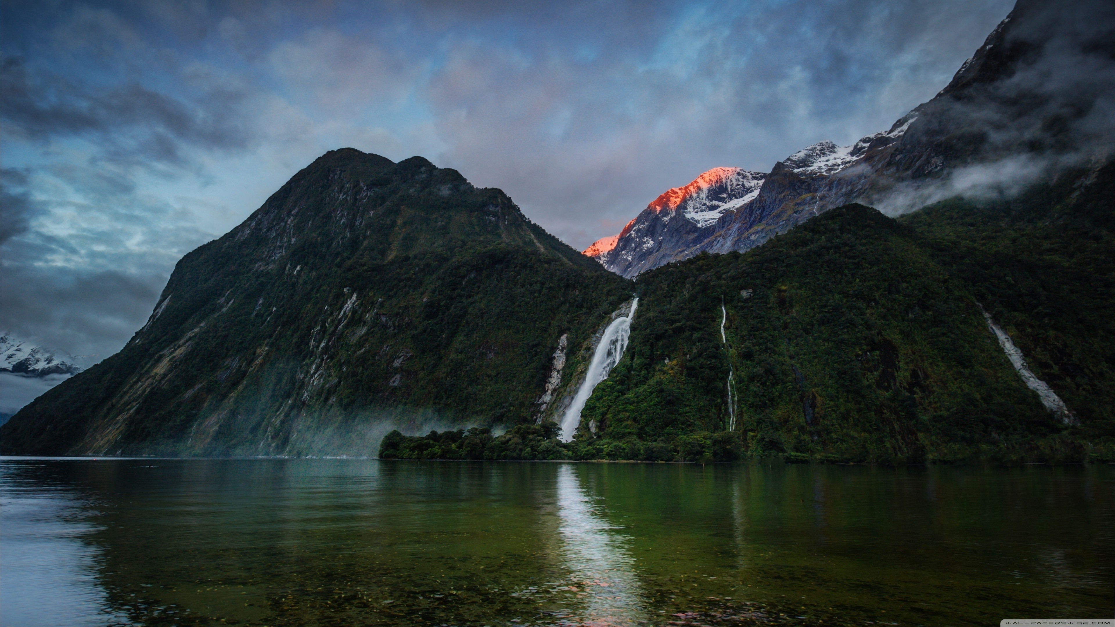 Waterfalls cascade down mountains into a lake HD Wallpaper