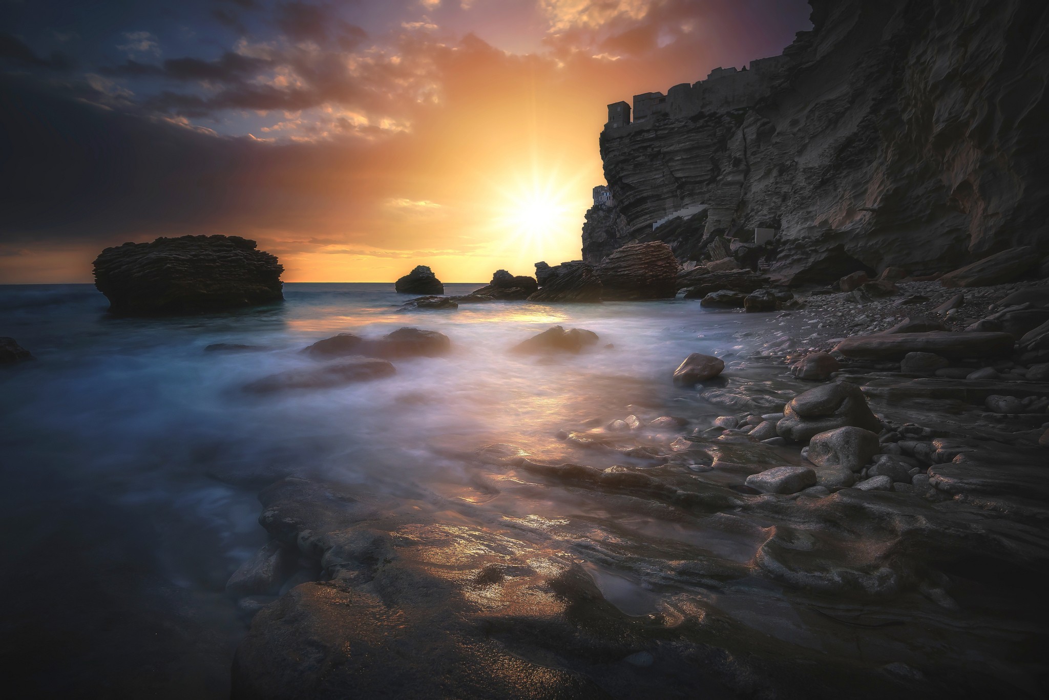 Sunset over rocky coastline with crashing waves HD Wallpaper