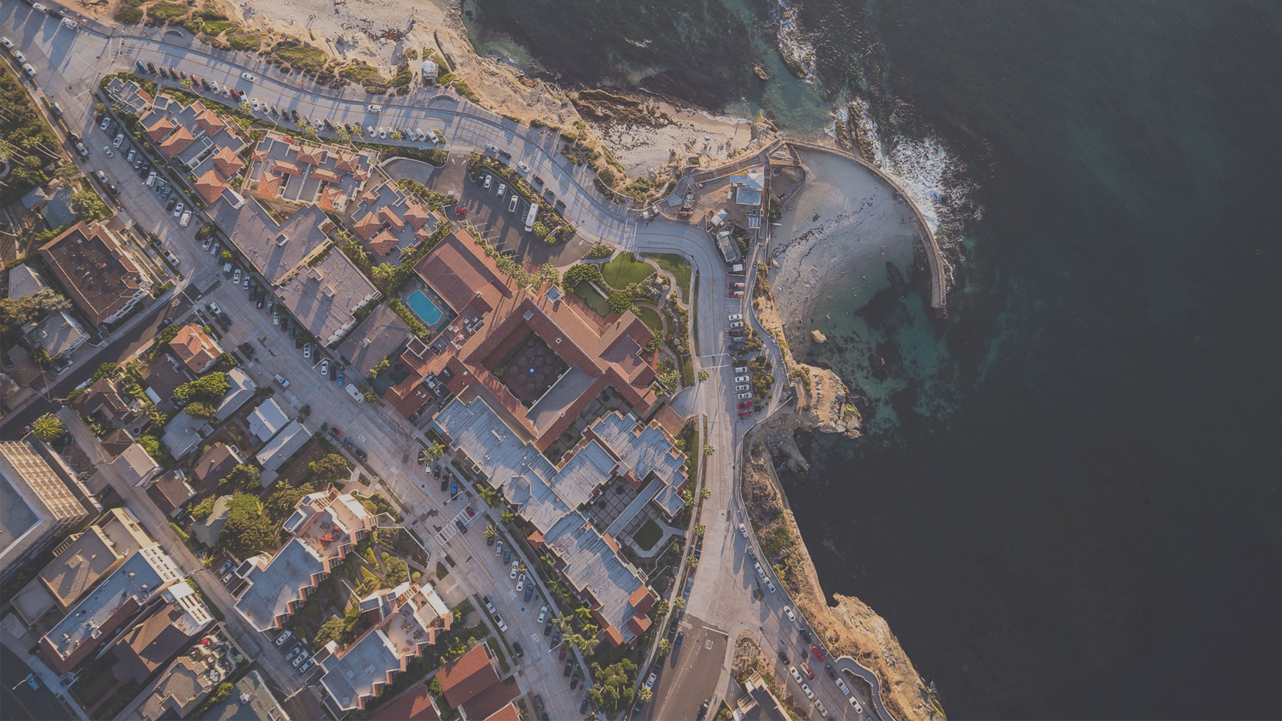 Aerial view of a coastal town with a beach and ocean HD Wallpaper